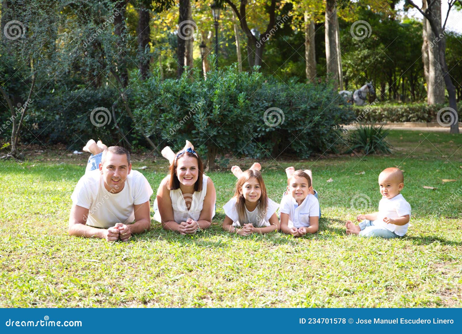 Portrait of Happy Parents with Their Three Children Lying in the Park