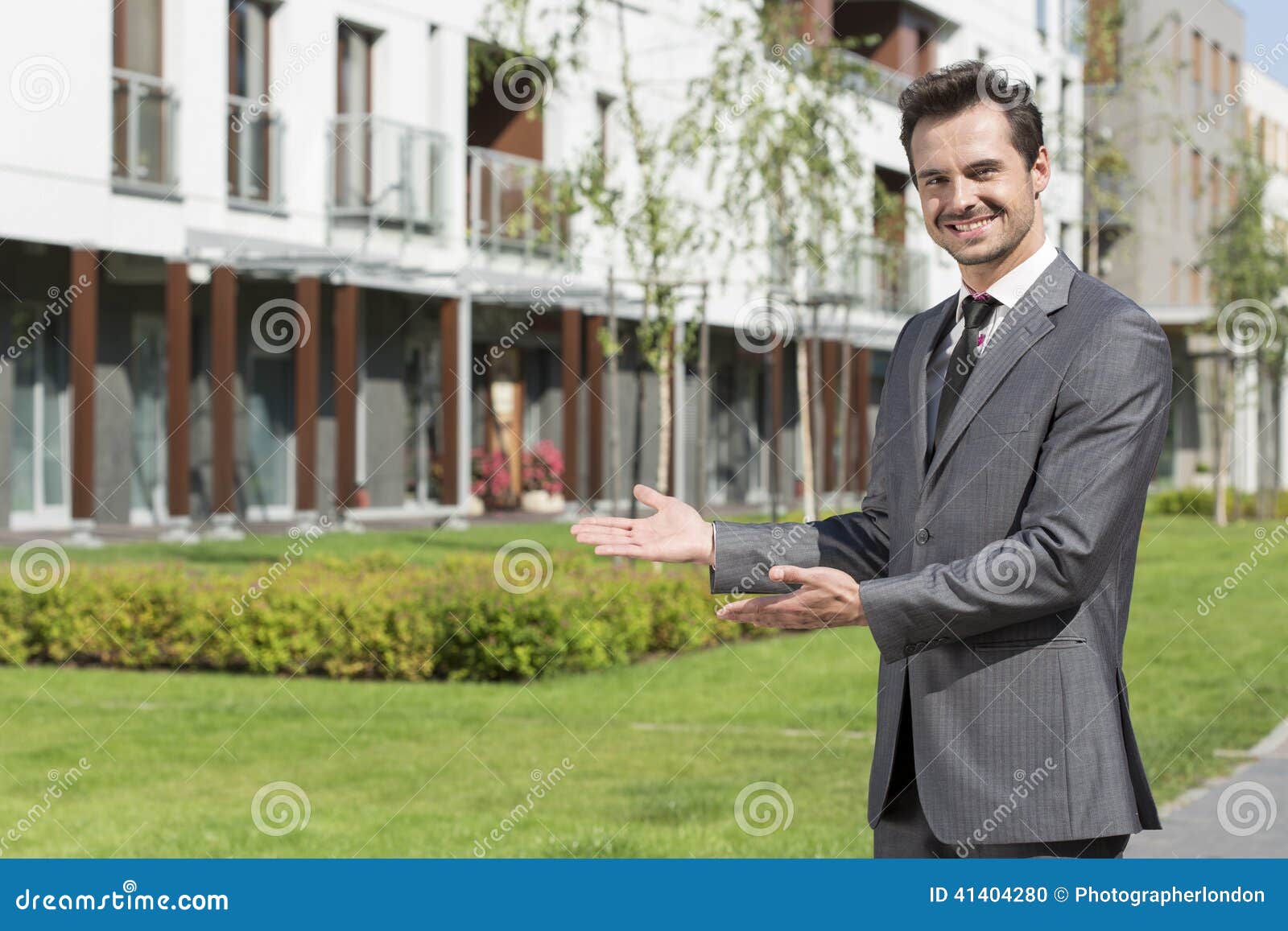 Portrait of Happy Real Estate Agent Presenting Office Building Stock