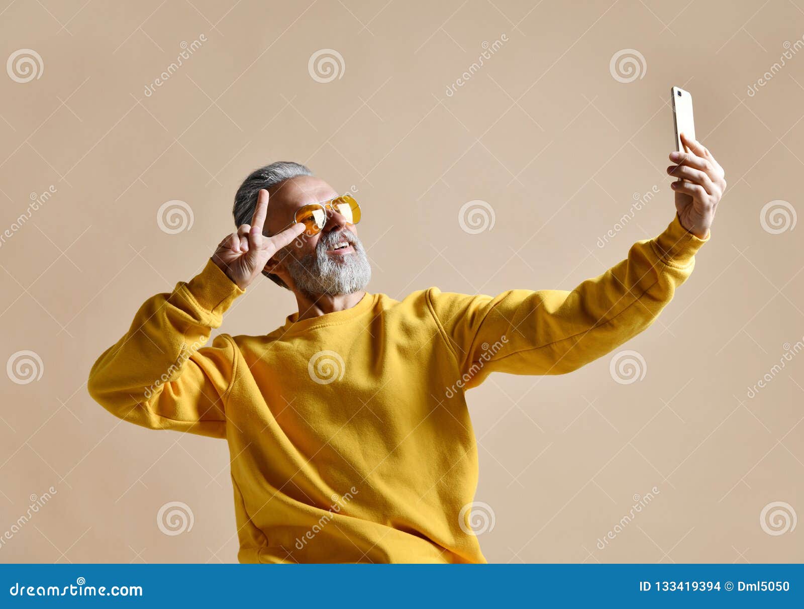 portrait of happy senior millionaire man using smartphone cellphone make selfie in yellow sunglasses