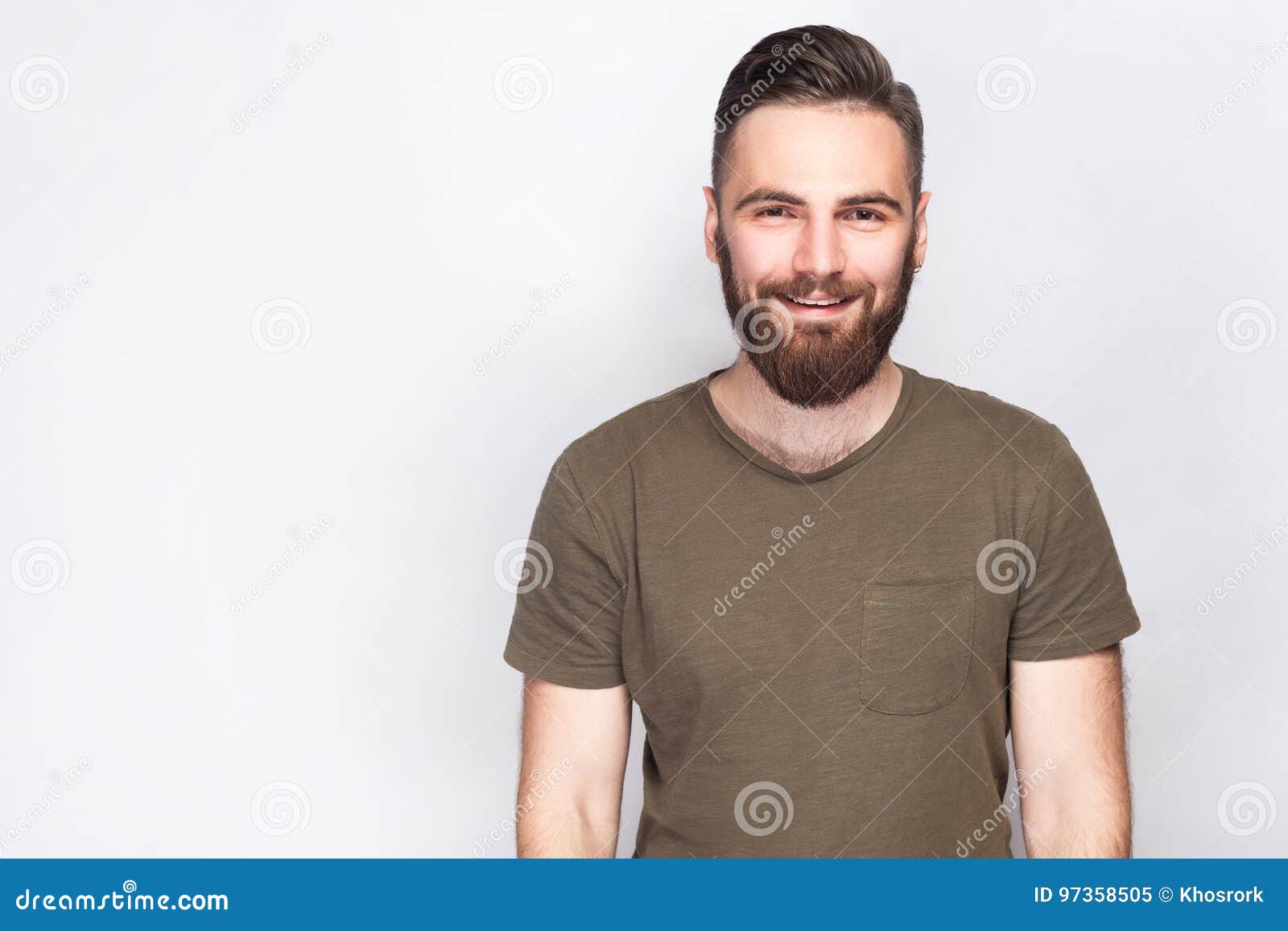 portrait of happy smiley bearded man with dark green t shirt against light gray background.