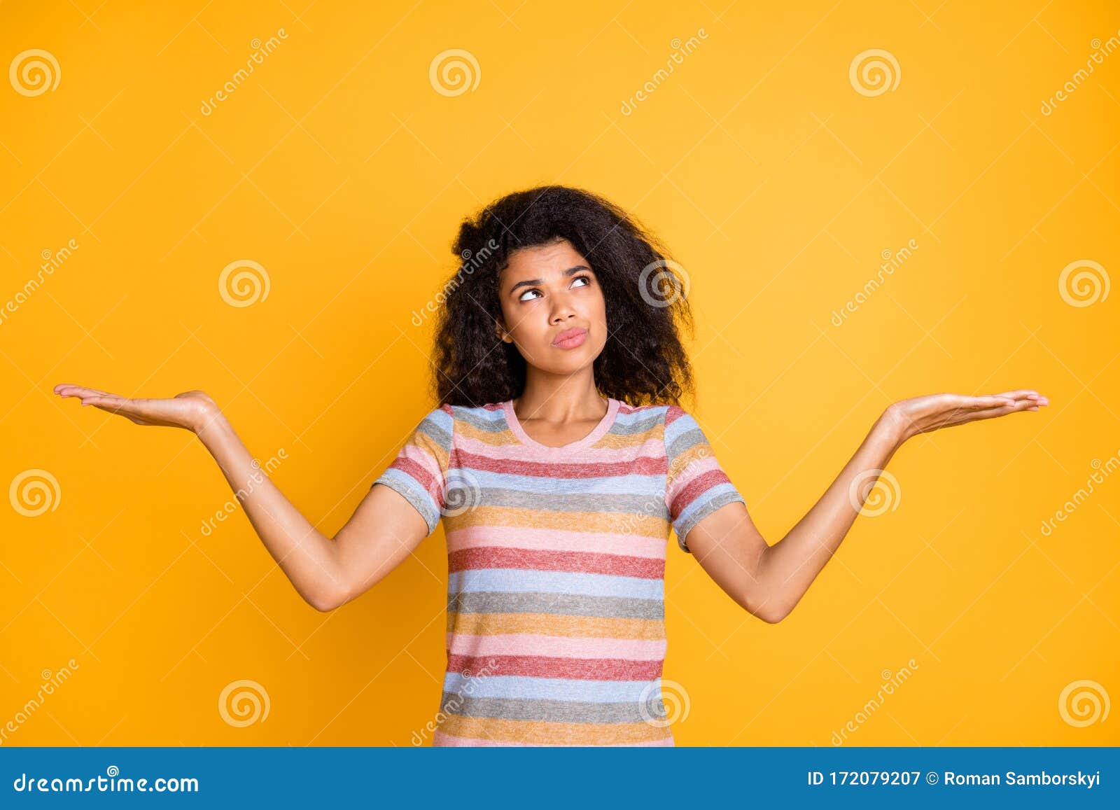 portrait of her she nice attractive doubtful wavy-haired girl in striped tshirt holding on palms invisible objects