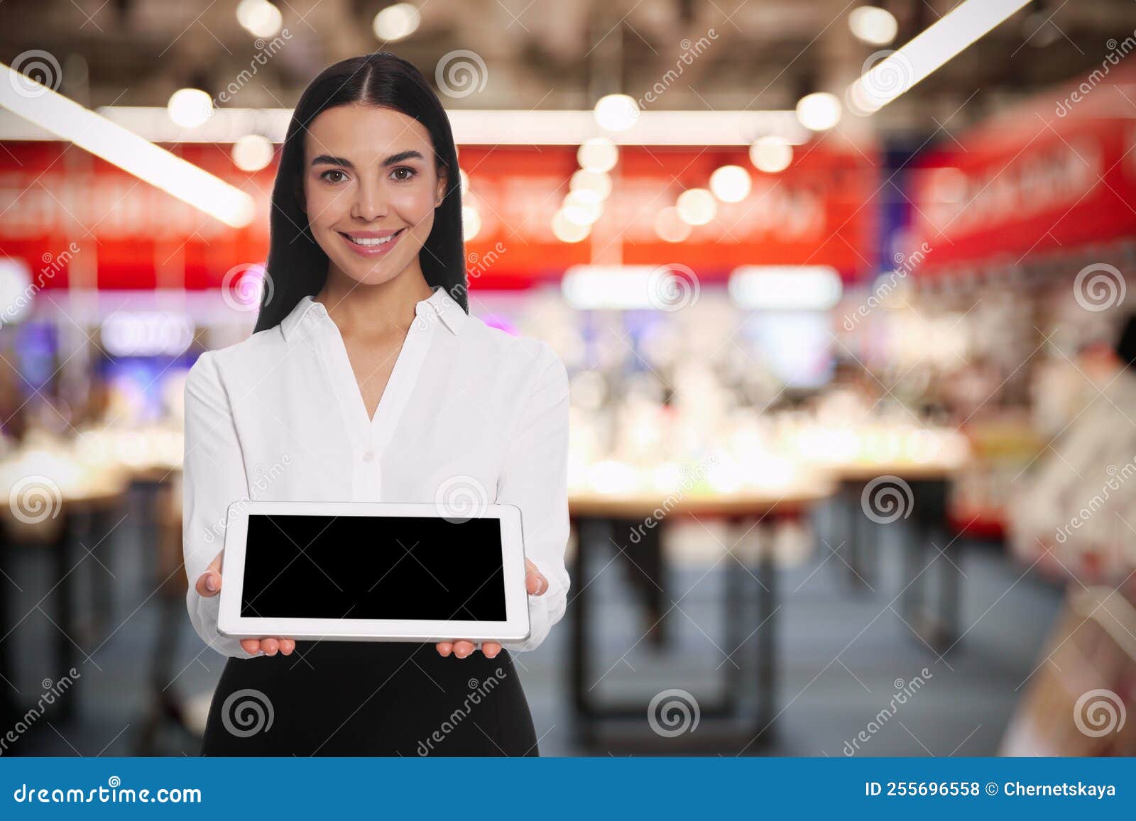 Portrait of Hostess Wearing Uniform with Tablet in Shopping Mall. Space