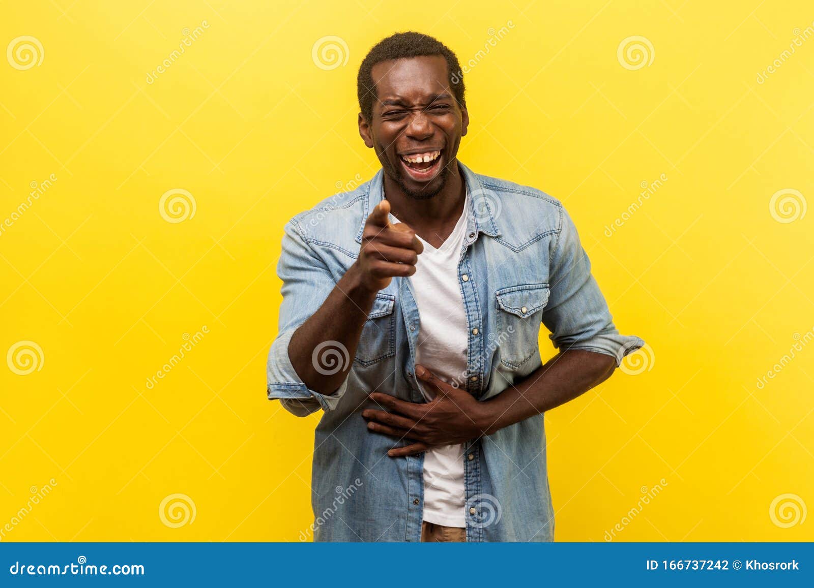 portrait of joyful positive man laughing out loud. indoor studio shot  on yellow background