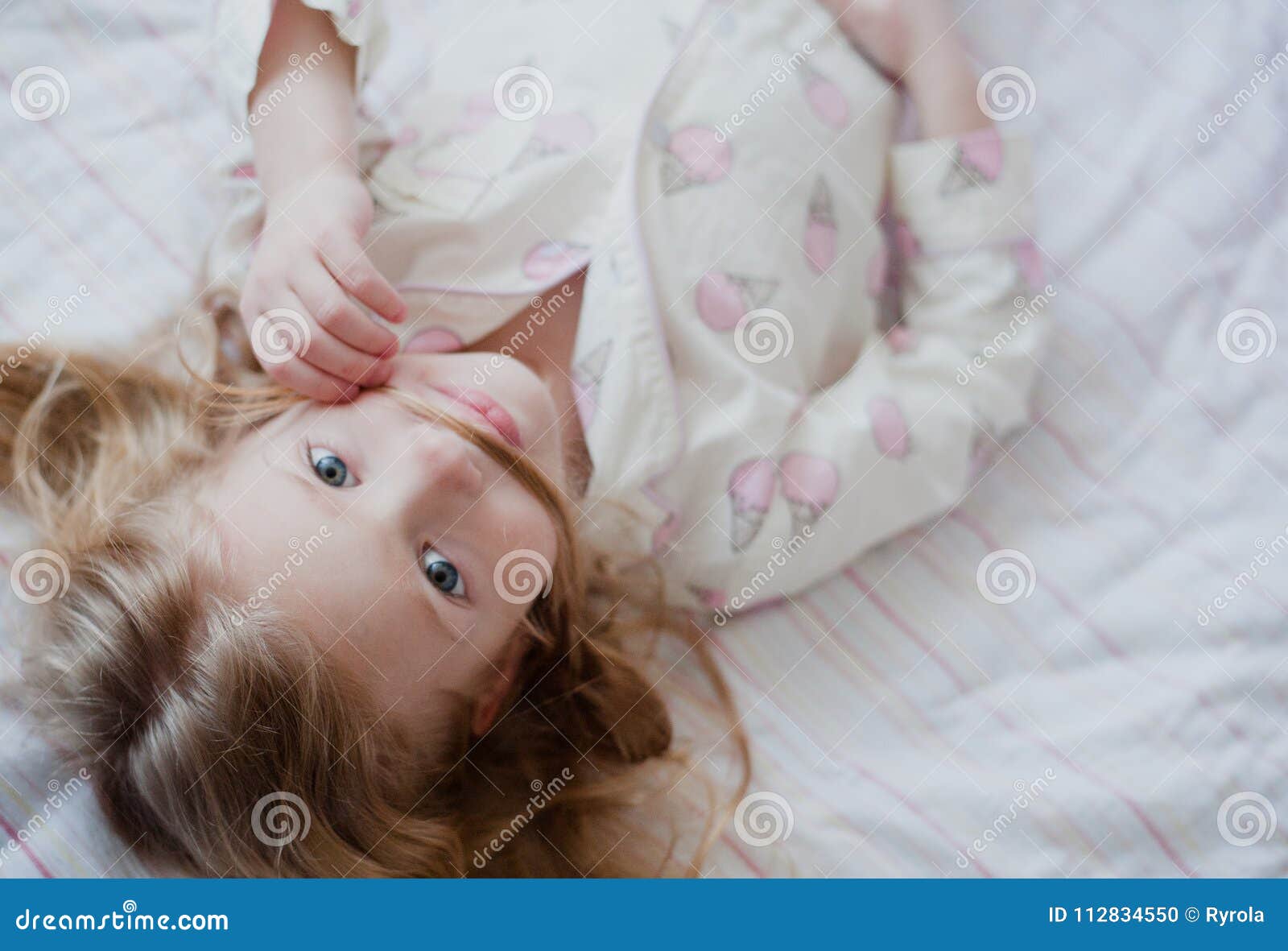 Portrait of Little Blonde Girl in Pink Pajamas Making Mustache Out