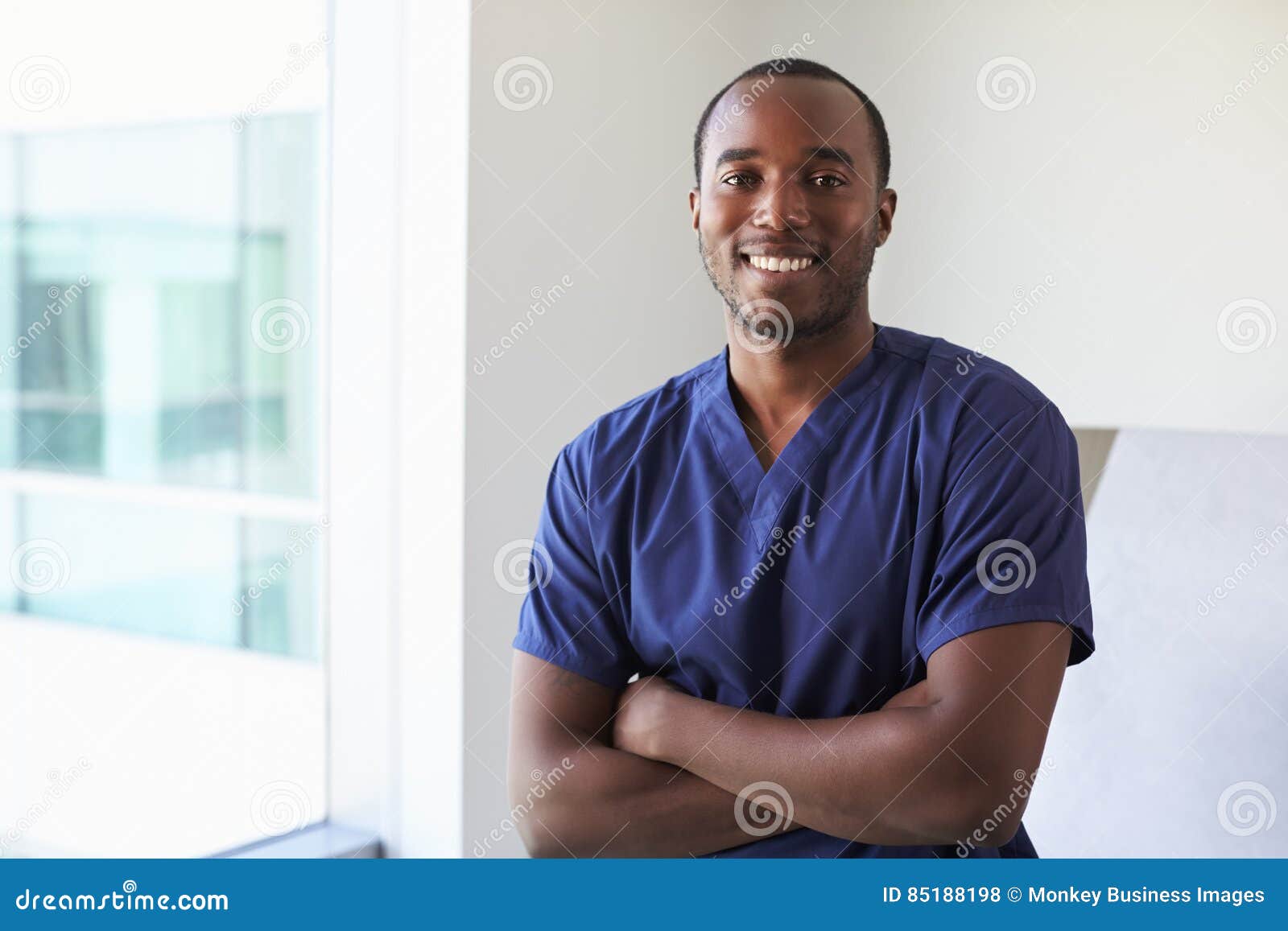 portrait of male nurse wearing scrubs in exam room