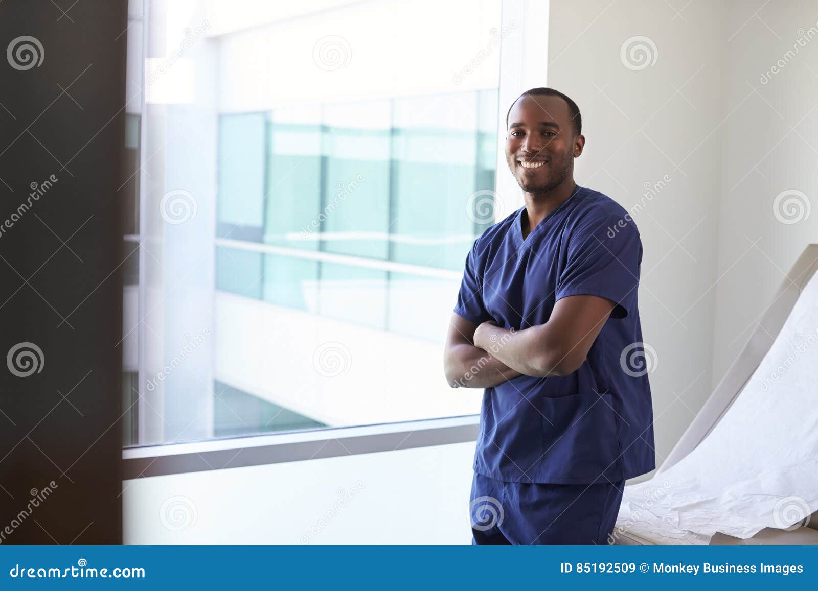 portrait of male nurse wearing scrubs in exam room