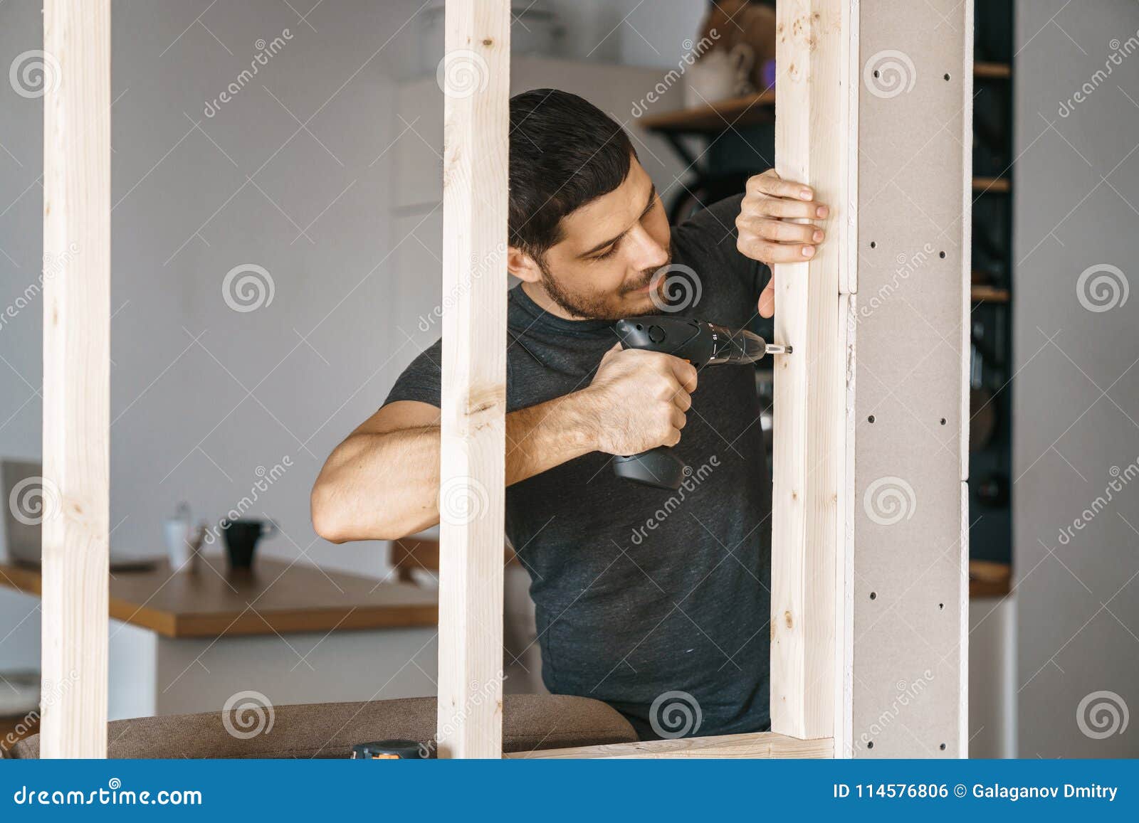 portrait of a man in home clothes with a screwdriver in his hand fixes a wooden construction for a window in his house. repair