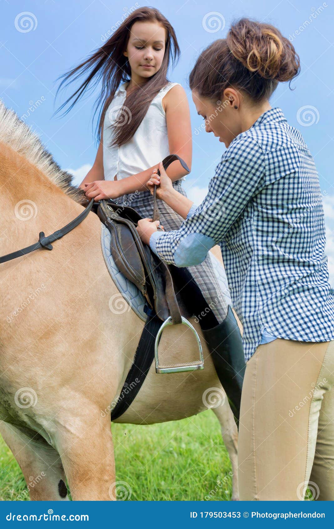 portrait of mature woman adjusting leathers on horse for stirrup iron in ranch
