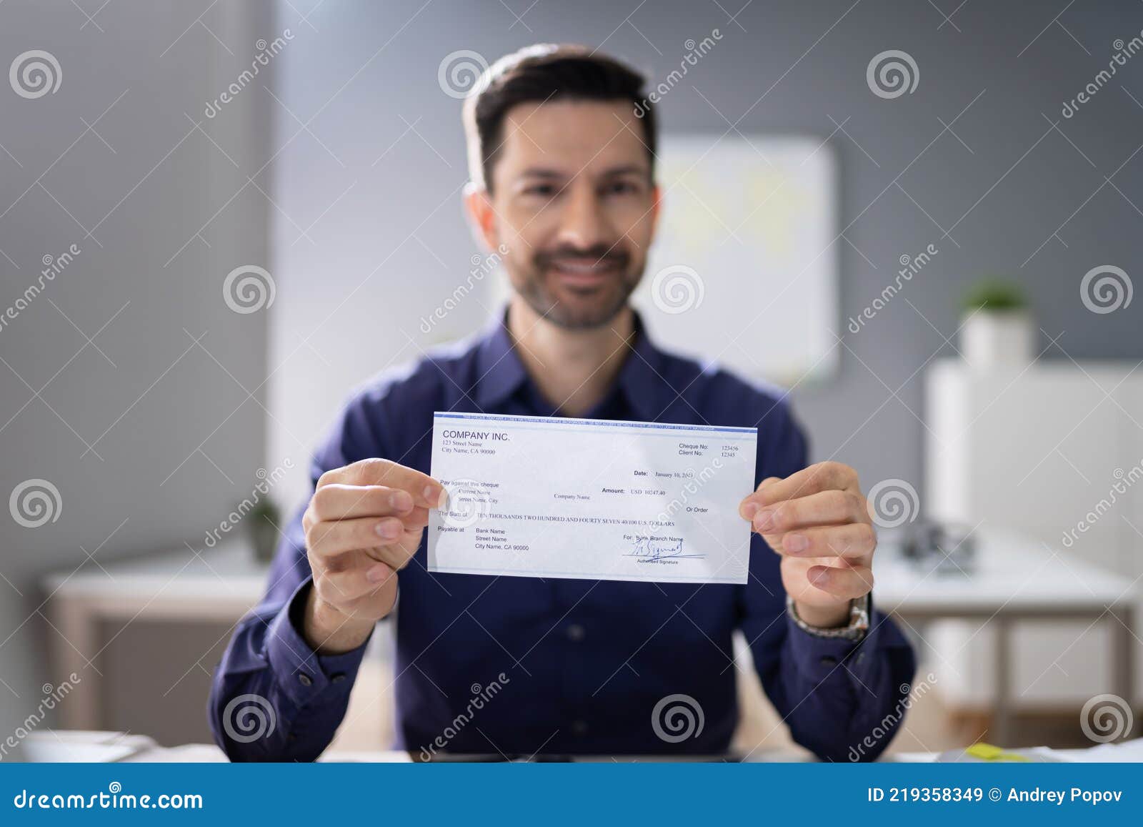 smiling businessman holding cheque