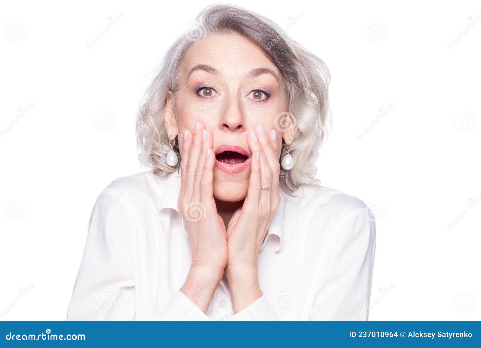 Portrait Of A Modern Mature Woman Looking At Camera With Open Mouth And Hands At Her Face Scared