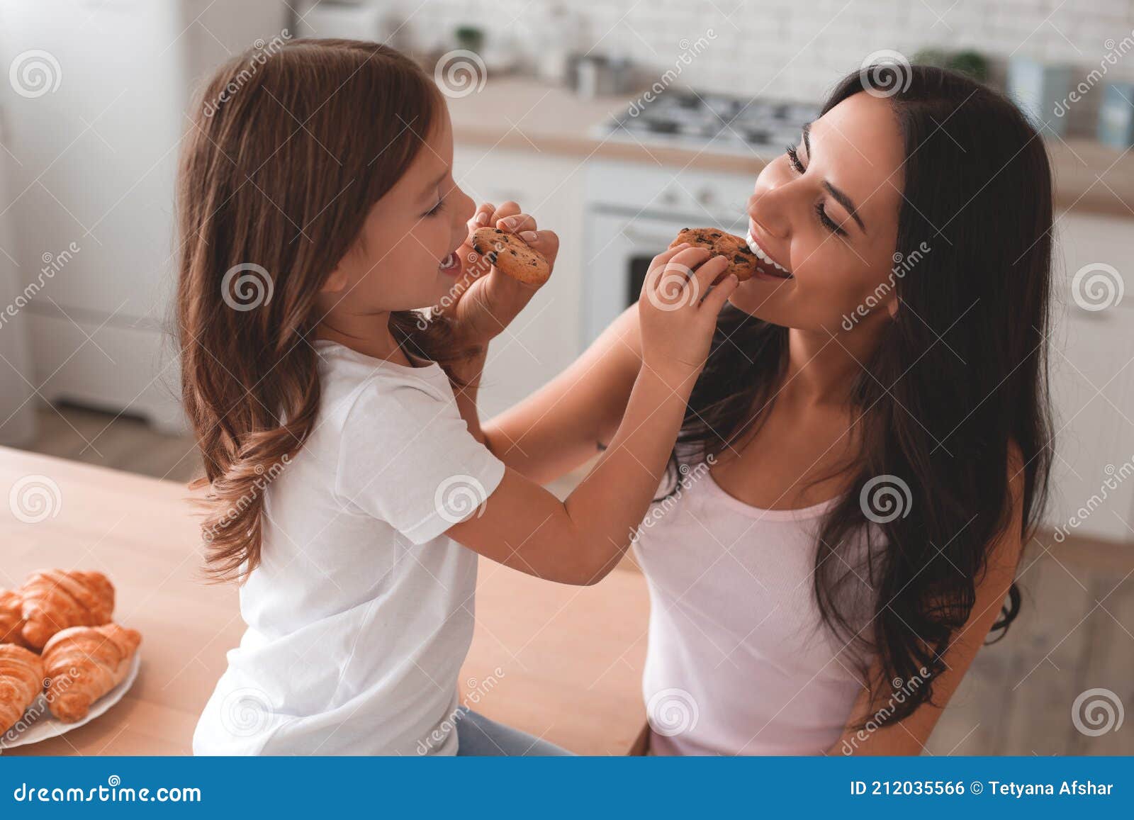 Portrait of Mother and Daughter Feeding Each Other with Biscuits on the