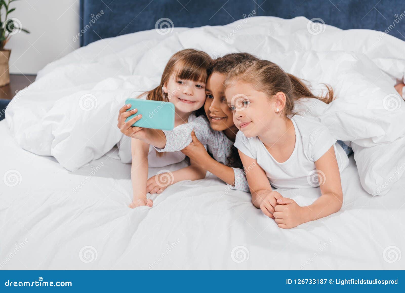 Portrait of Multiethnic Smiling Girls Taking Selfie while Lying Under ...