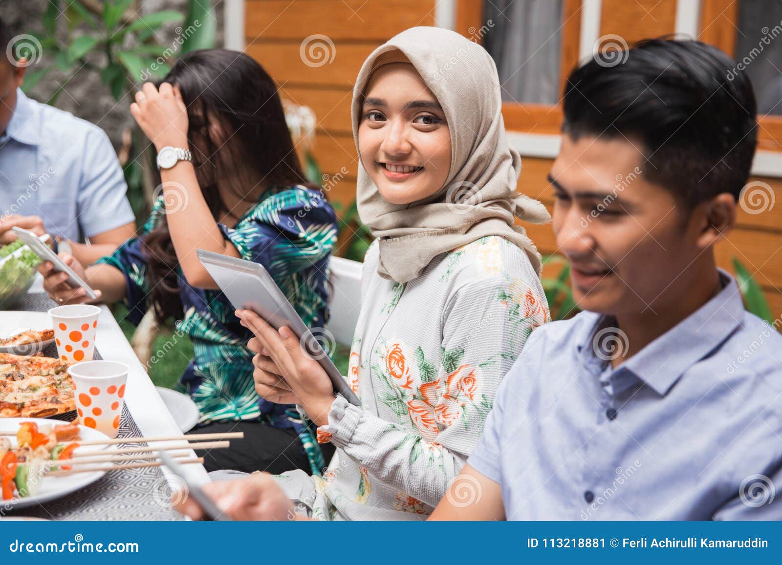 Muslim Asian Woman Using Tab While With Friends Stock