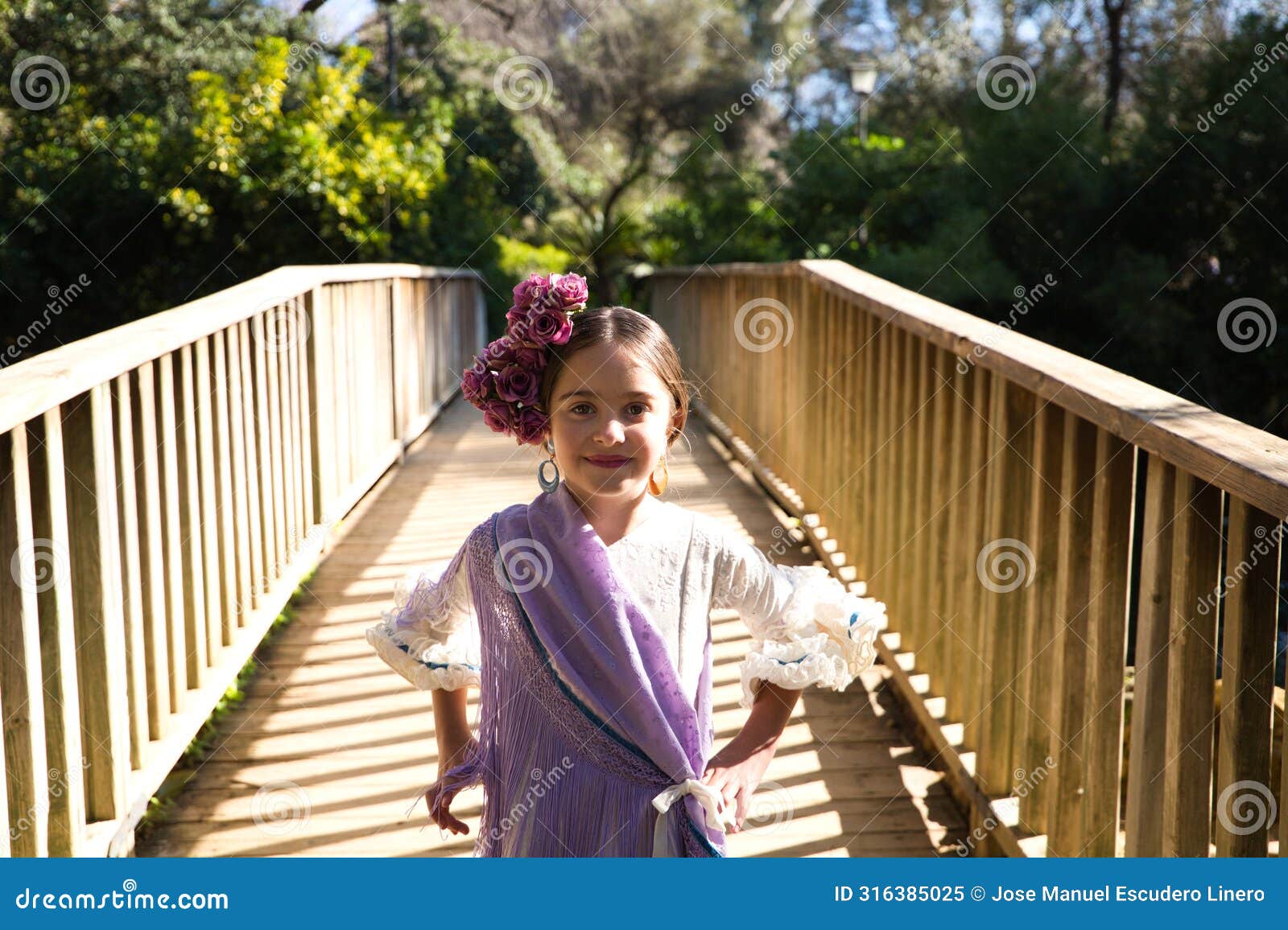portrait of a pretty girl dancing flamenco in a dress with frills and fringes typical of gypsies, walking on a wooden bridge in a