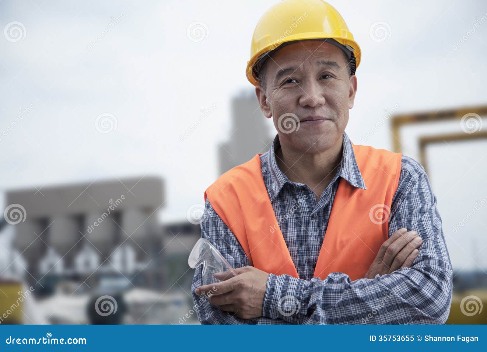 portrait of proud worker with arms crossed in protective workwear outside of a factory