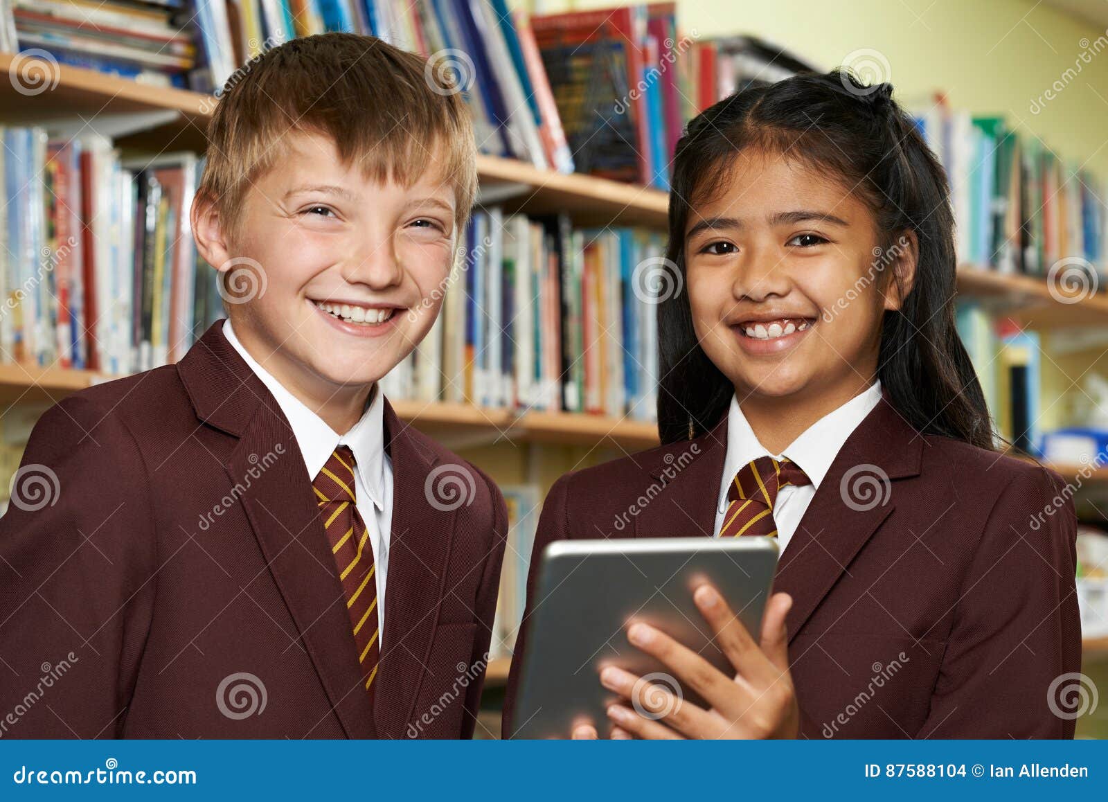 portrait of pupils wearing school uniform using digital tablet i