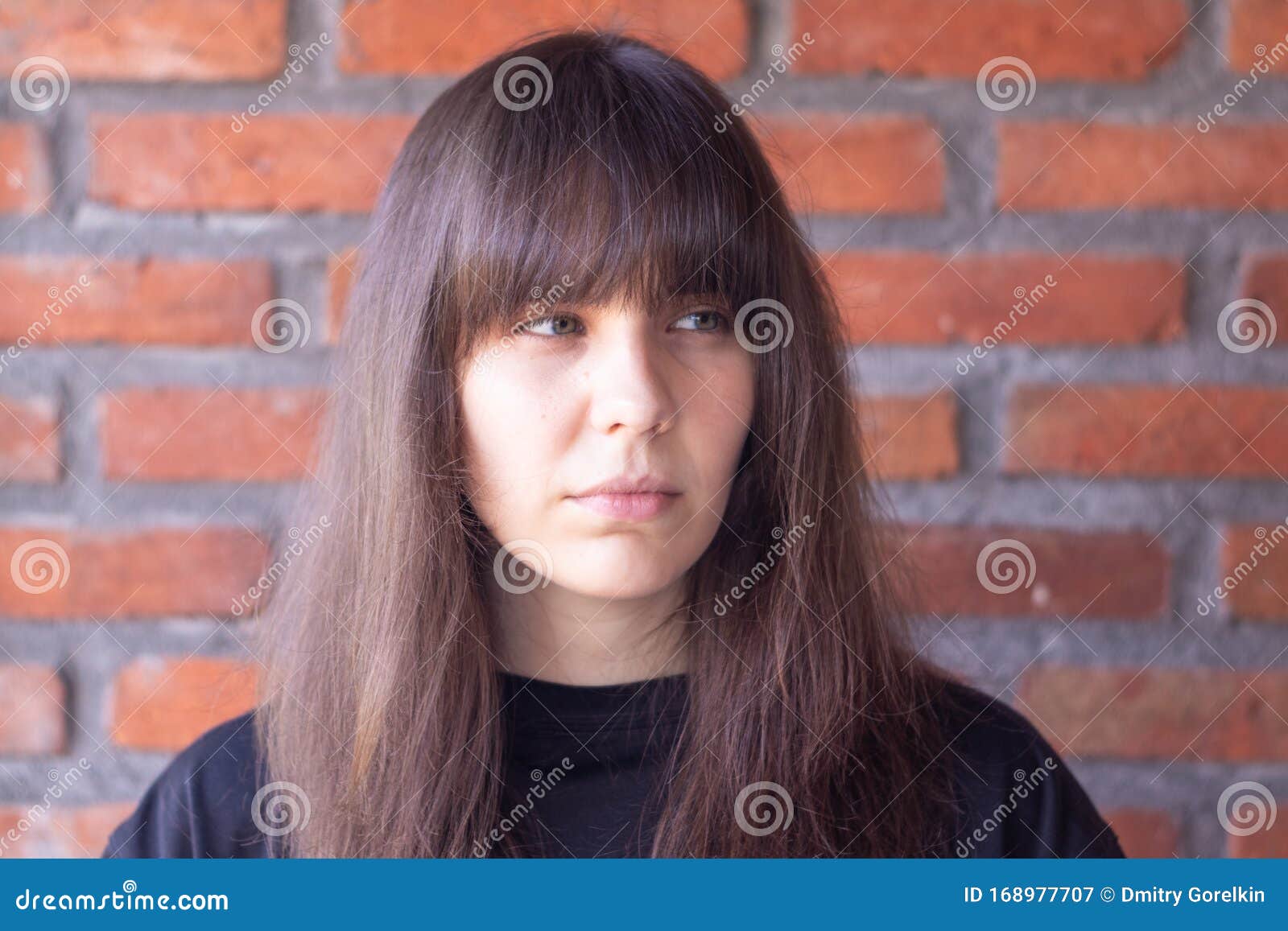 Portrait of a Sad Brunette Woman with Bangs Wearing a Black T-shirt on  Brick Wall Background Stock Image - Image of brunette, facial: 168977707
