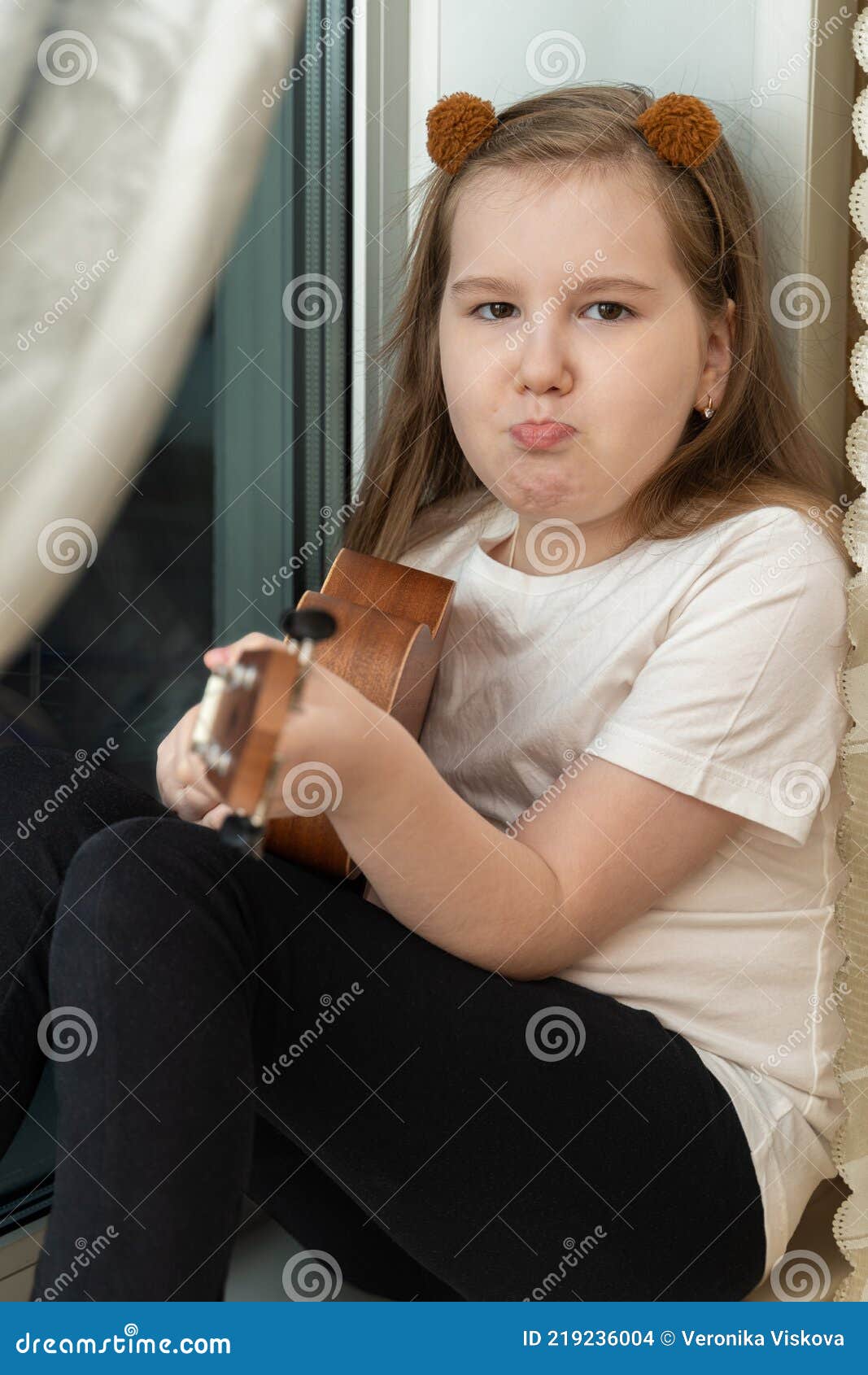 Portrait of Sad Upset Little Girl in White T-shirt and Black Leggings  Sitting Inside of Home and Playing Ukulele. Stock Photo - Image of cute,  education: 219236004