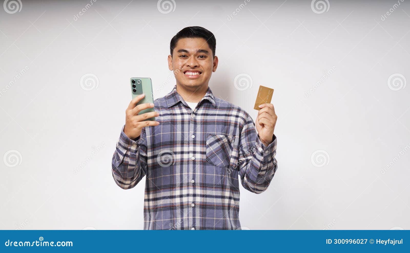 portrait of satisfied happy asian young man holding smart phone and credit card