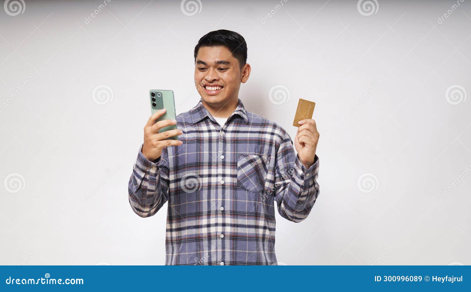 portrait of satisfied happy asian young man holding smart phone and credit card