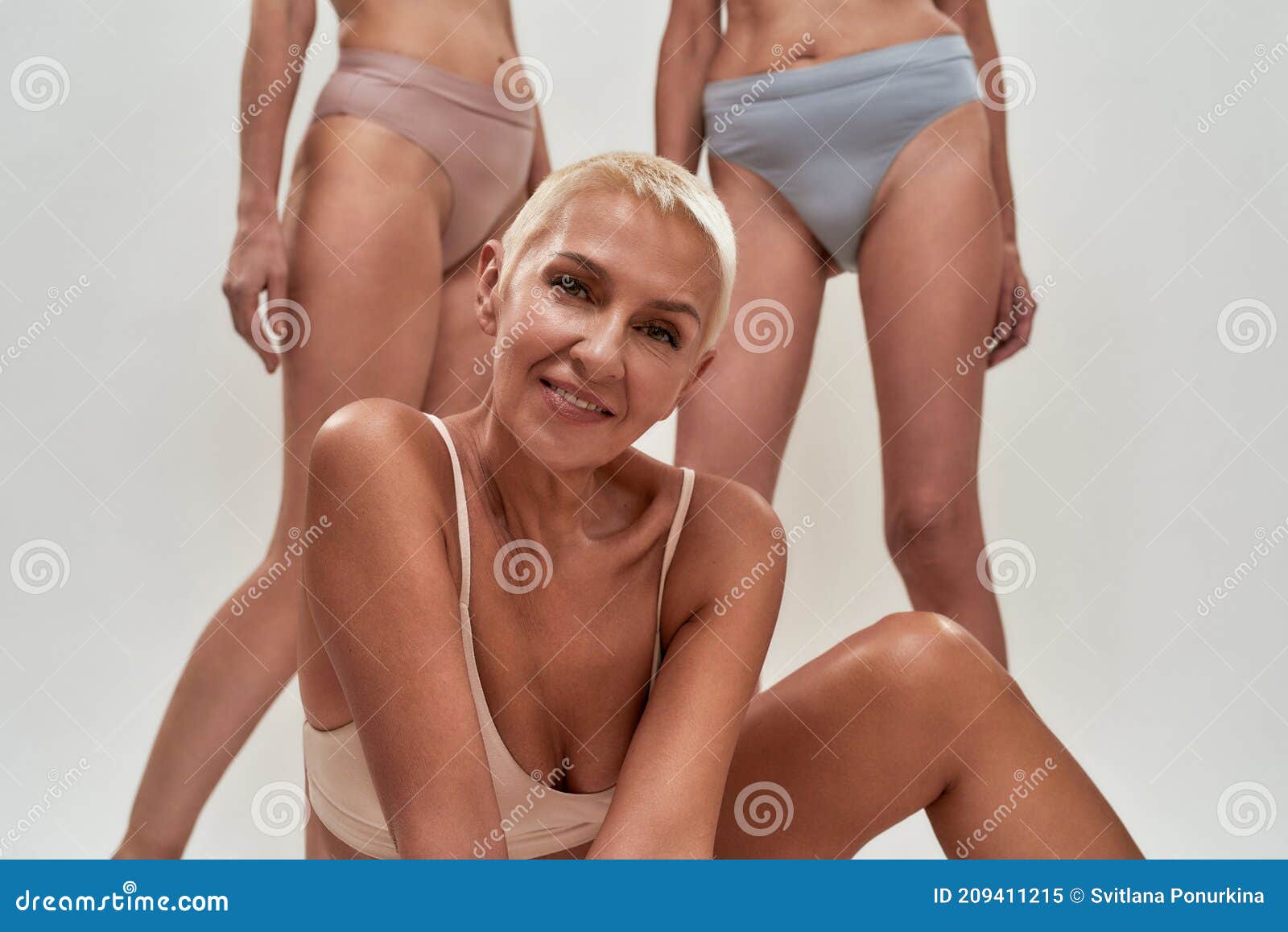 Portrait of Sensual Caucasian Senior Woman with Short Hair Wearing Underwear Smiling at Camera while Posing Half Naked Stock Image