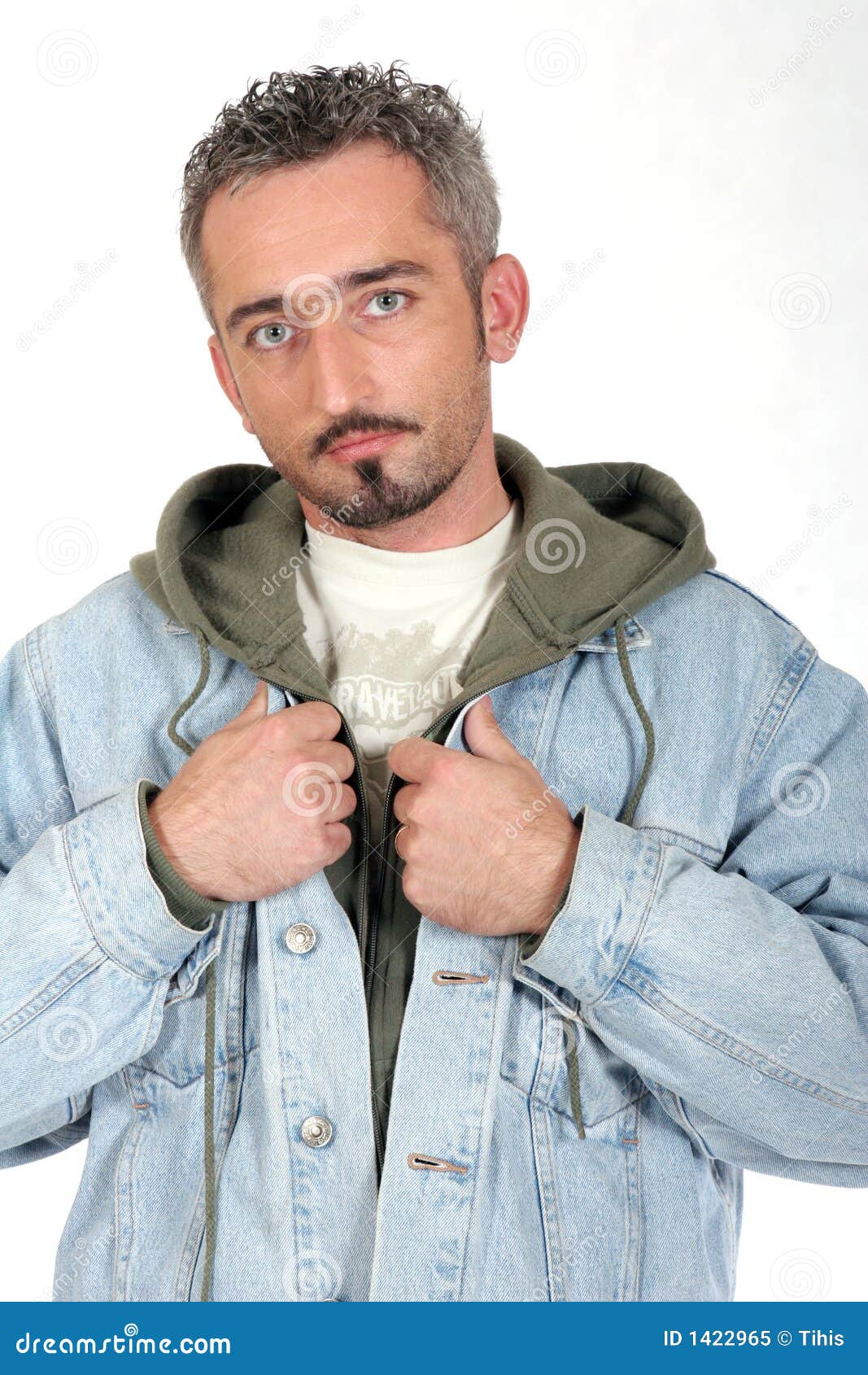 Portrait Of Serious Man 2. Portrait of a man with blue eyes, beard and mustache. Wearing casual clothes. Holding lapels of blue denim jacket with both hands. Serious expression. Shot from the waist up.