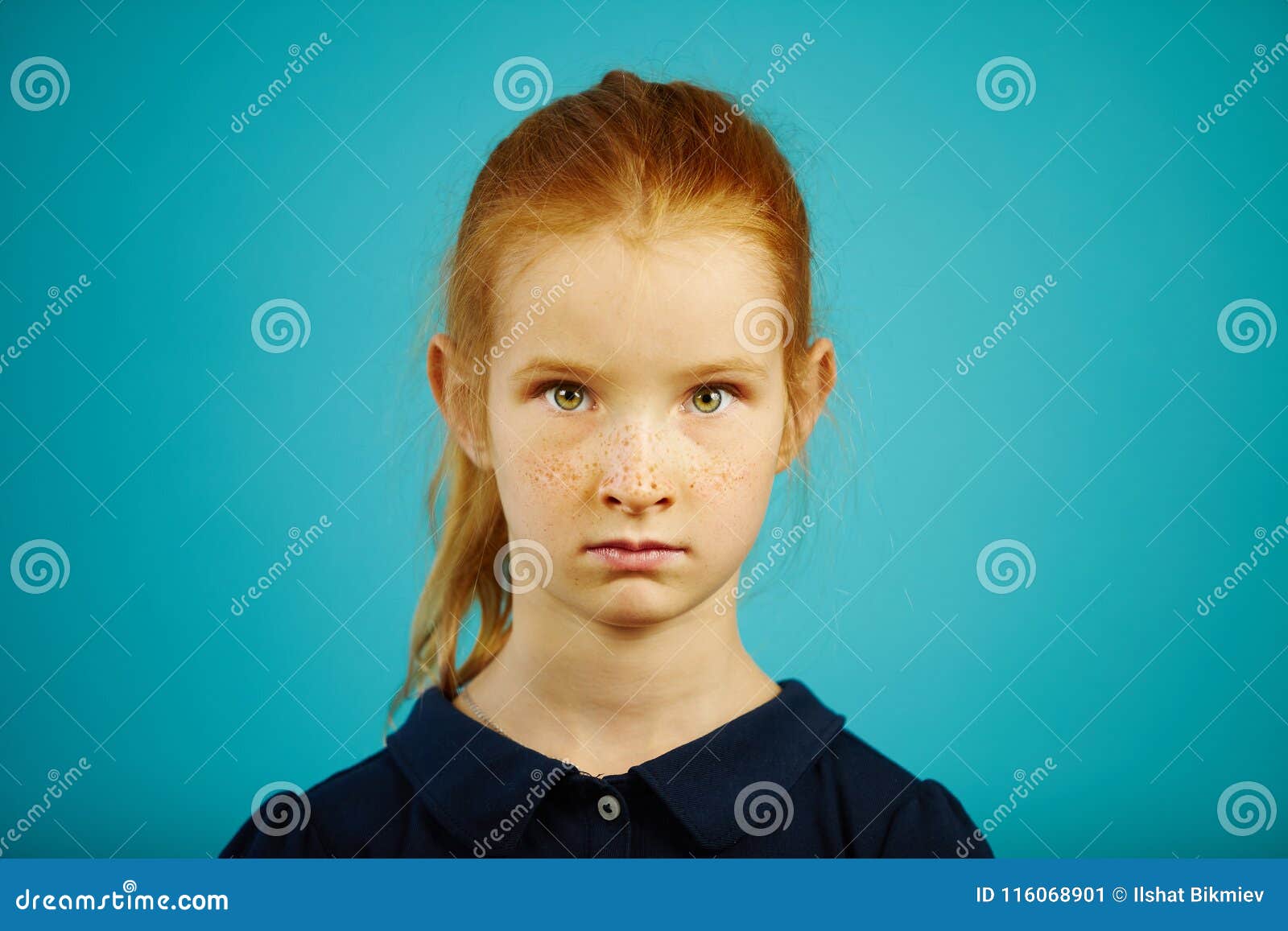 portrait of serious seven year old girl with freckles and red hair