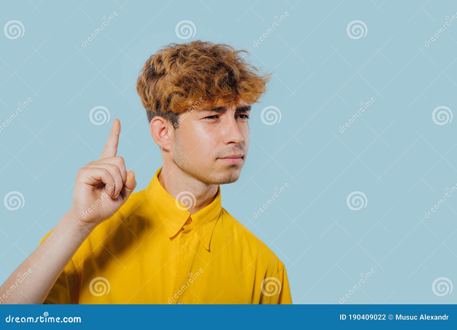 portrait of a seriously boy pointing fingers up, at copy space,