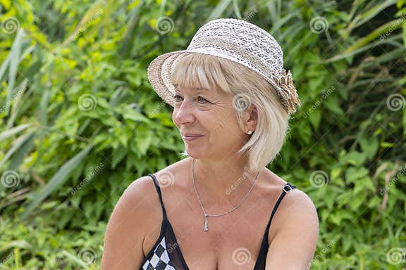 Portrait of a Elderly Woman 60-65 Years Old in a Straw Hat and Swimsuit