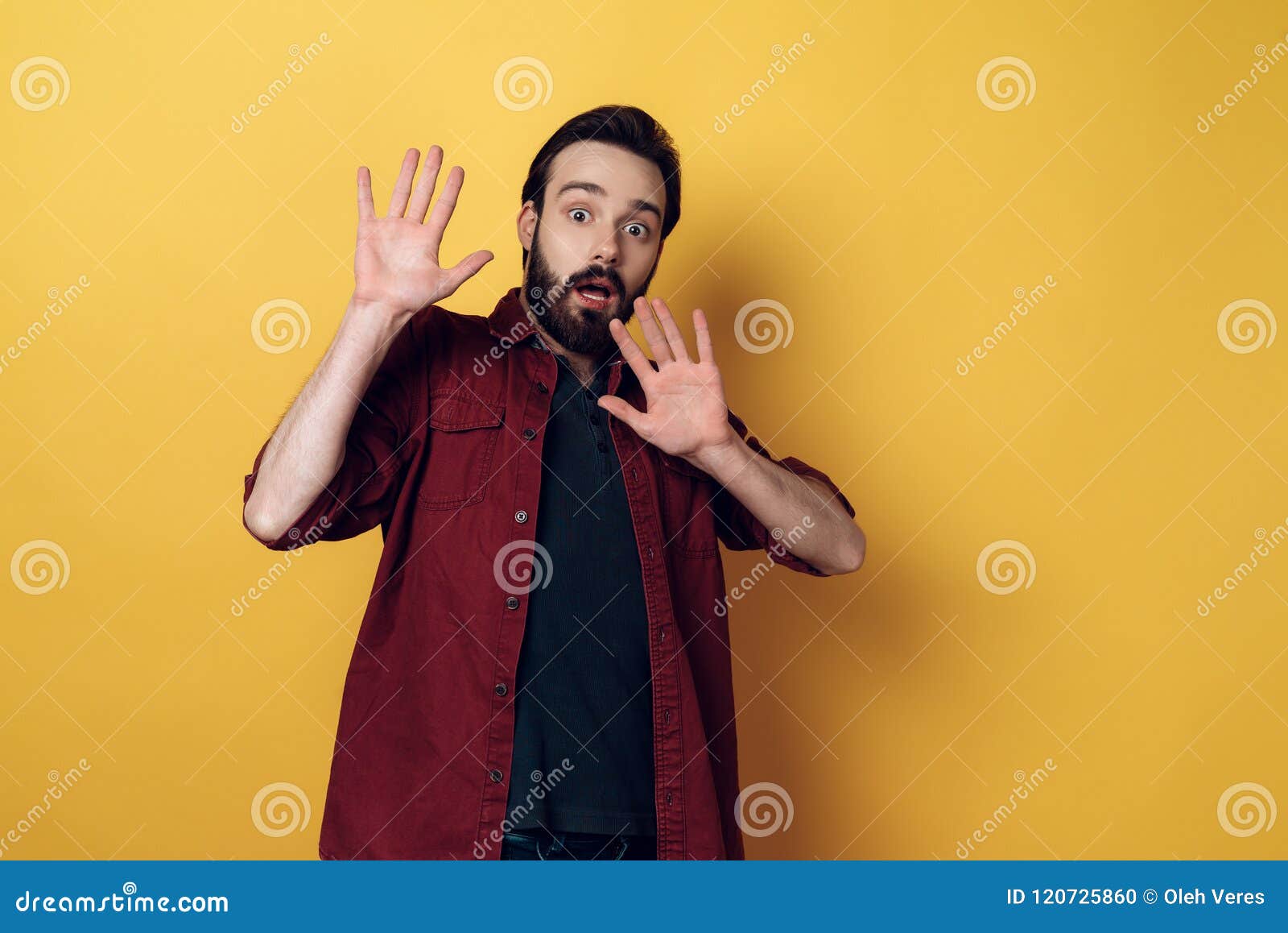 portrait of shocked bearded man keeps hands up