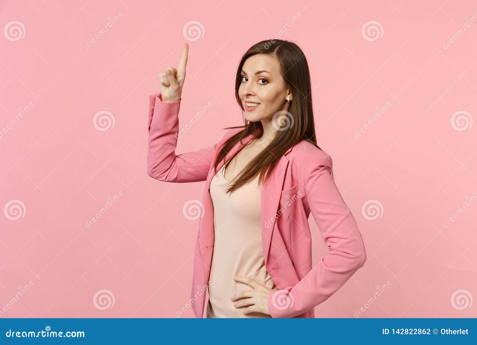 Portrait Of Smiling Beautiful Woman Wearing Jacket Standing Pointing Index Finger Up Isolated 