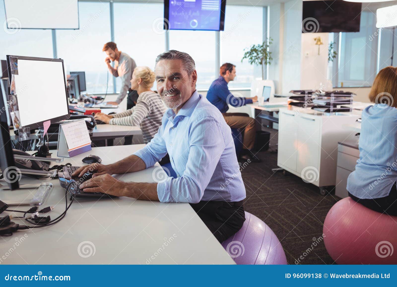 Portrait Of Smiling Businessman Working At Desk While Sitting On