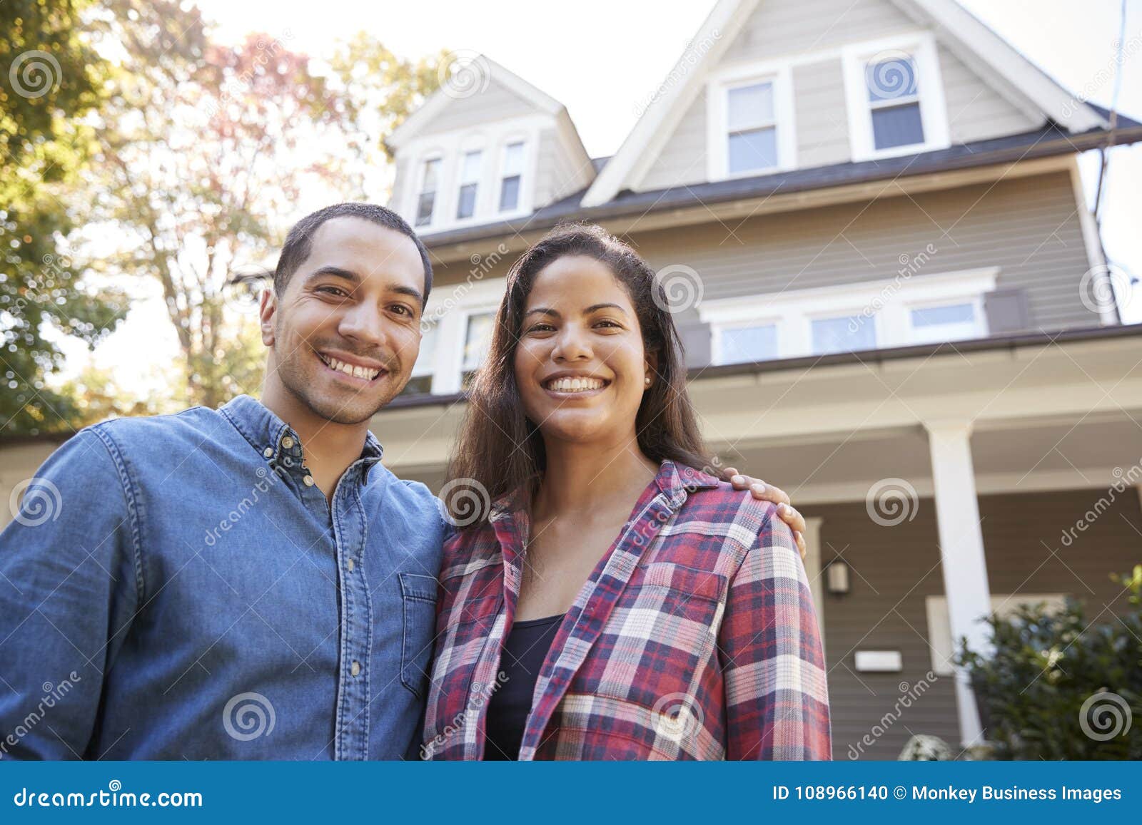 portrait of smiling couple standing in front of their home