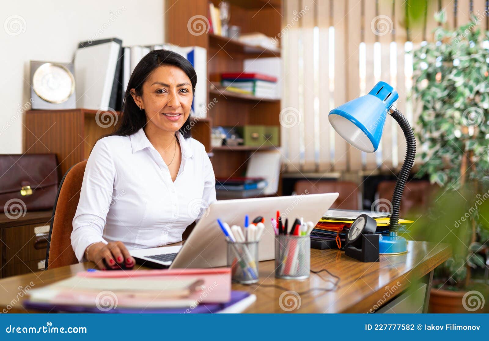 Smiling Hispanic Businesswoman Working with Laptop in Office Stock ...