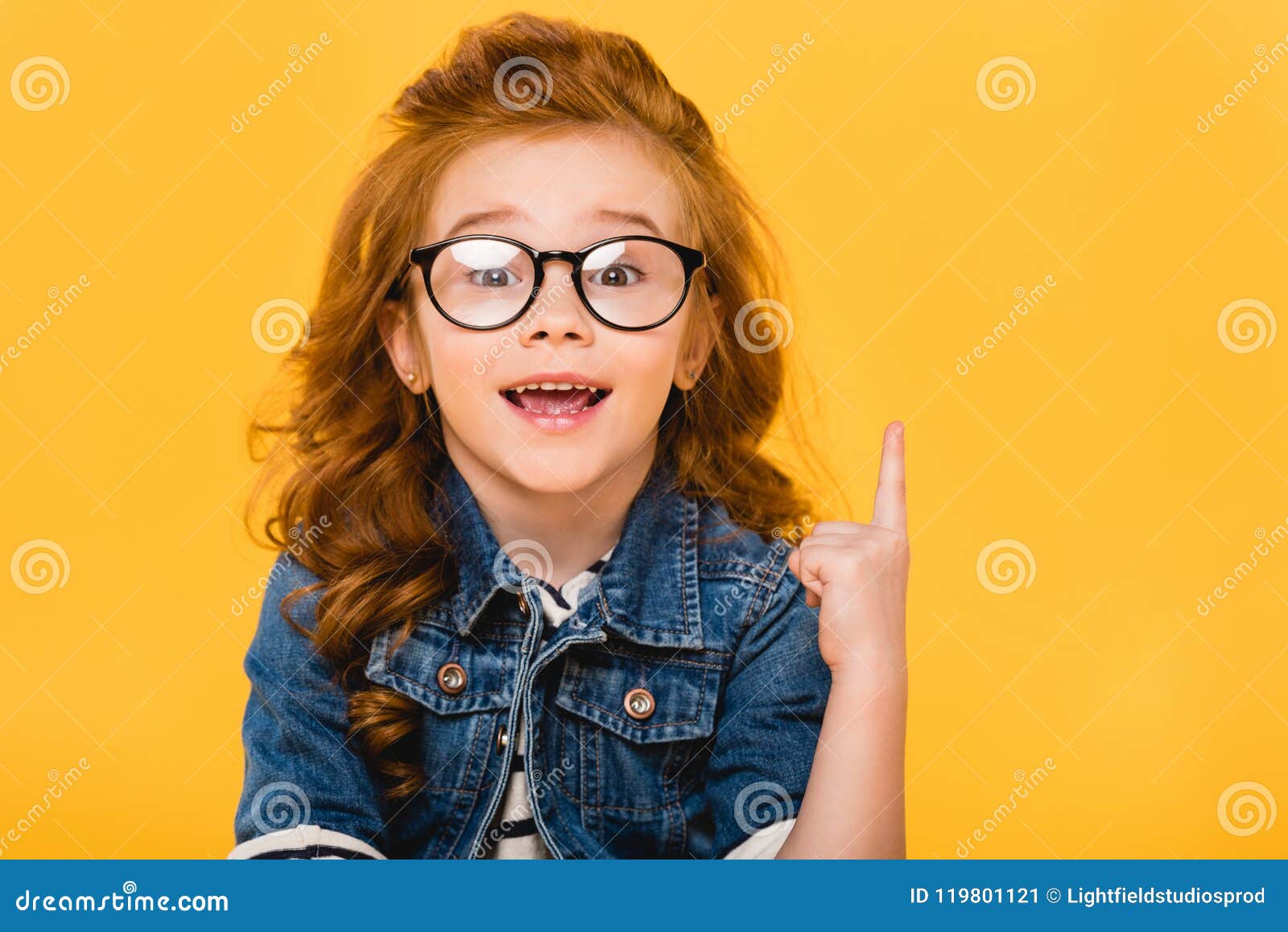 portrait of smiling little kid in eyeglasses pointing up