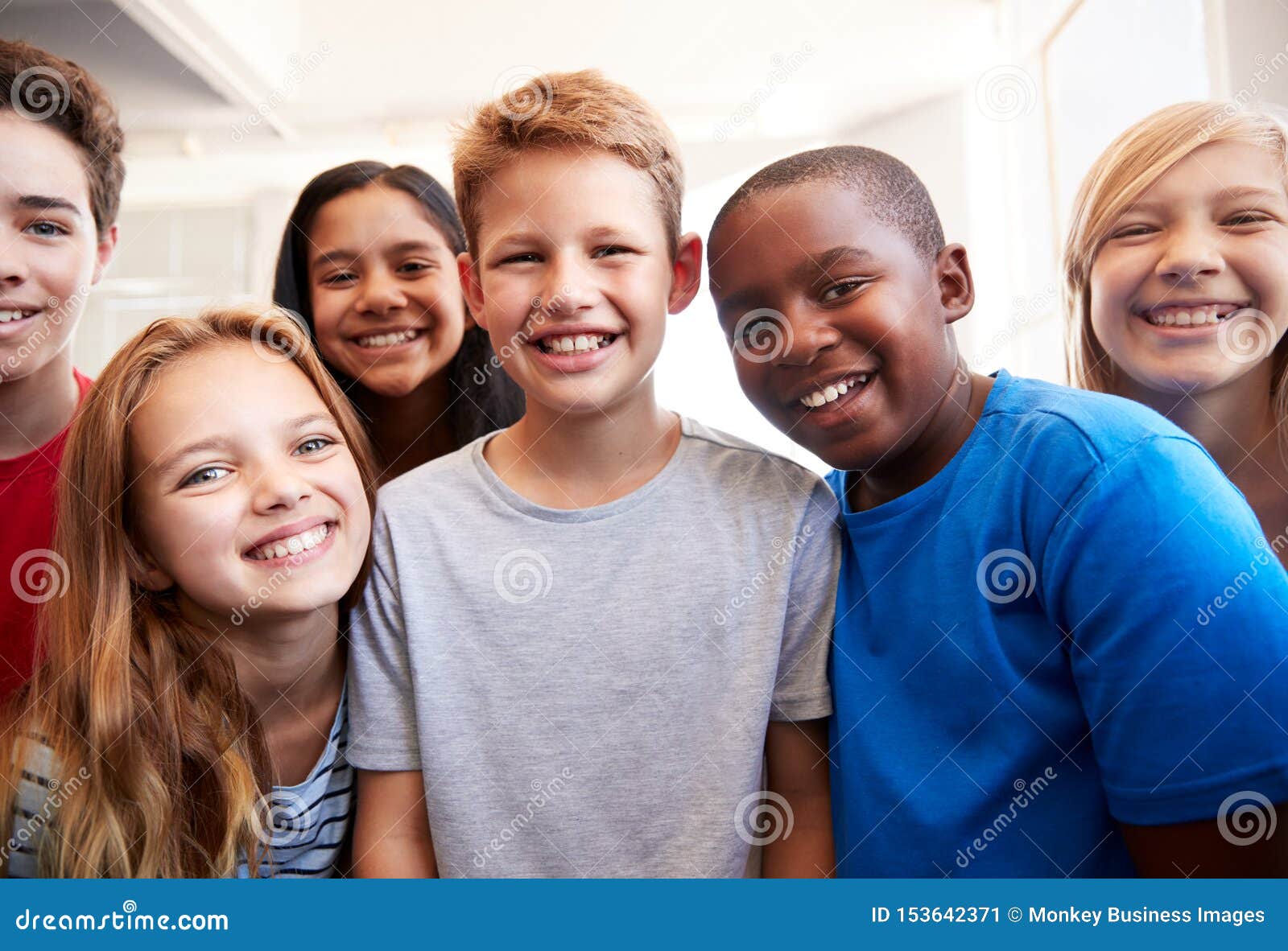 portrait of smiling male and female students in grade school classroom