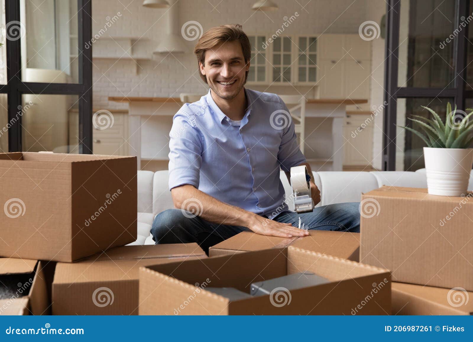 portrait of smiling man pack boxes relocating to new home