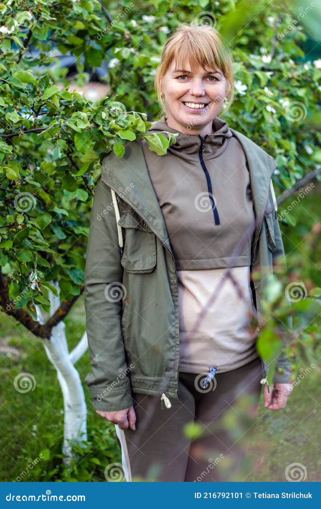 portrait of smiling mature woman standing in garden. countryside. posing for the camera in the spring garden. happiness