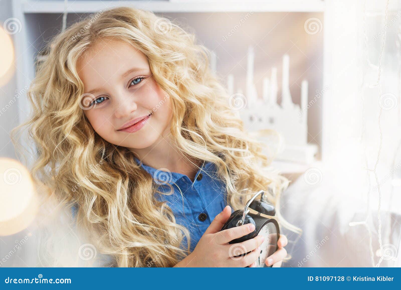 portrait-of-smiling-pretty-little-girl-with-a-clock-at-hands-near-the