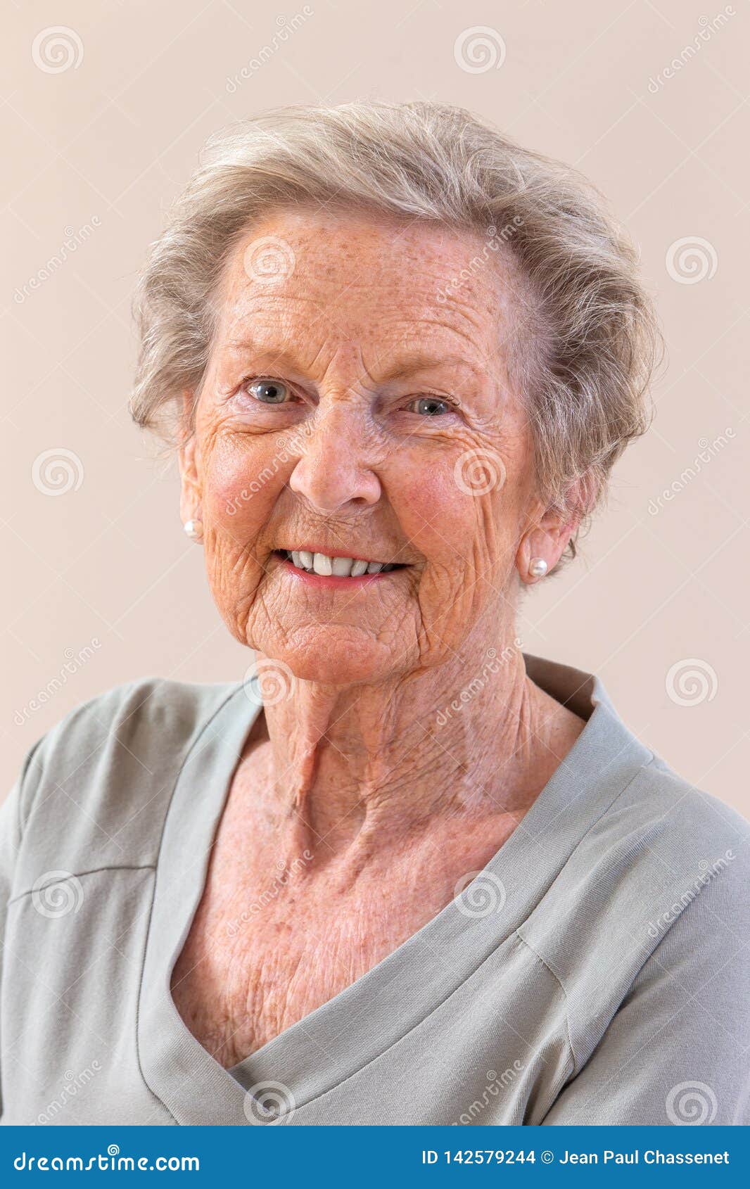Closeup Portrait Of Smiling Senior Woman Against Gray 