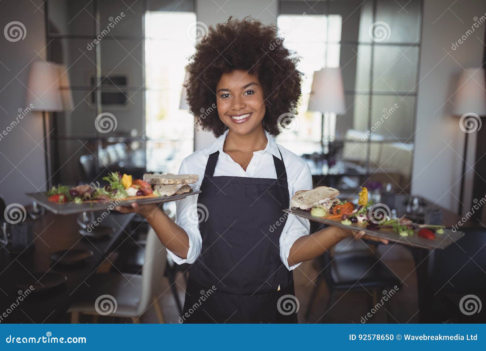 portrait of smiling waitress holding food tray