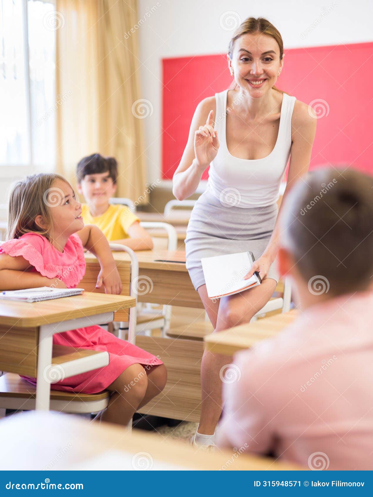 portrait of smiling woman teacher during lesson with tweens