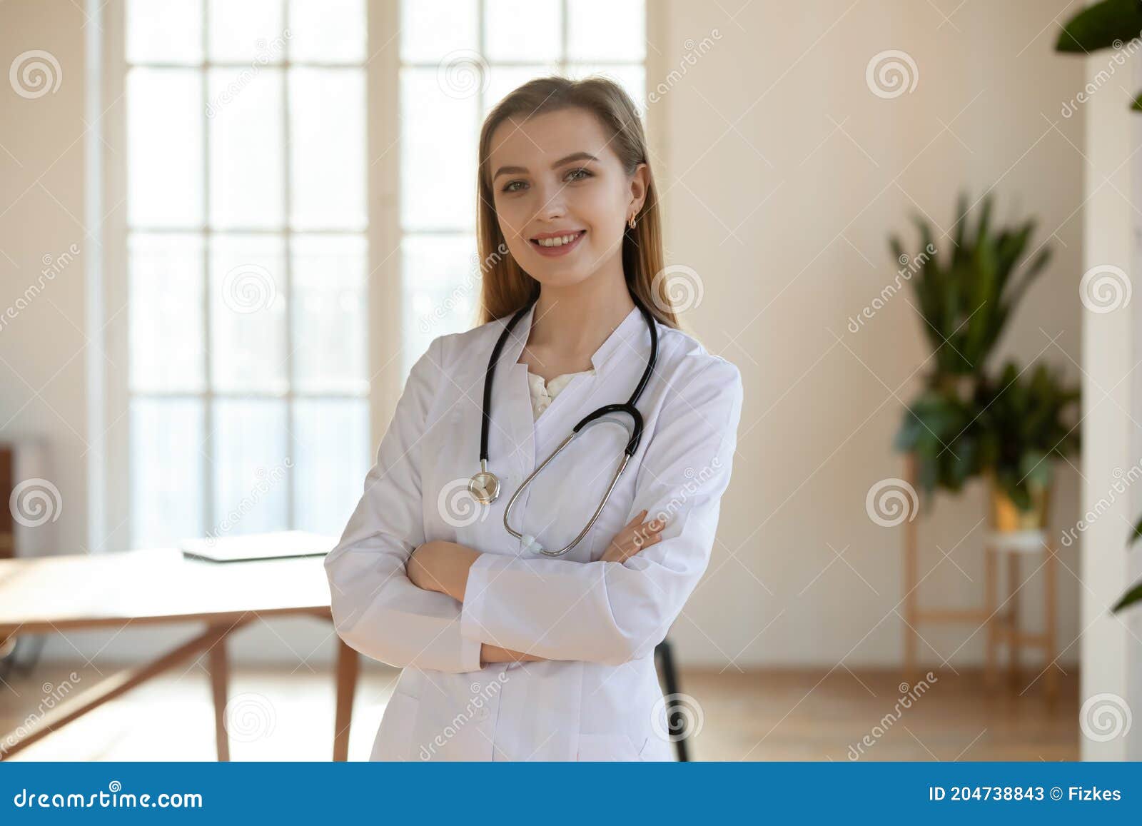 Portrait of a young attractive doctor in white coat with stethoscope posing  in the hospital. Stock Photo by ASphotostudio