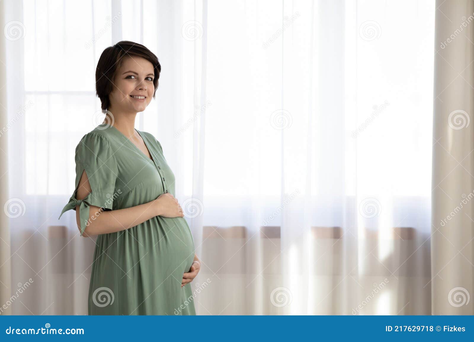 portrait of smiling pregnant woman caress belly bump