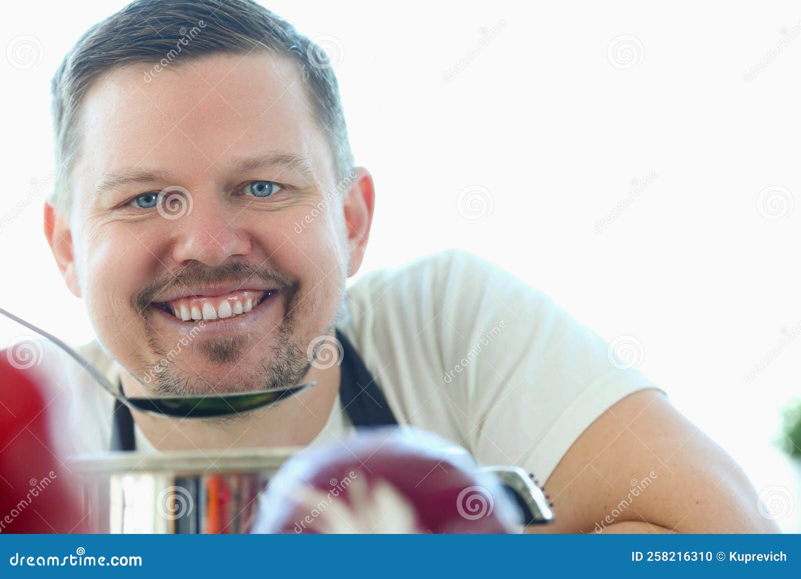 Portrait of Smiling Young Chef Tasting Food in Kitchen Stock Photo