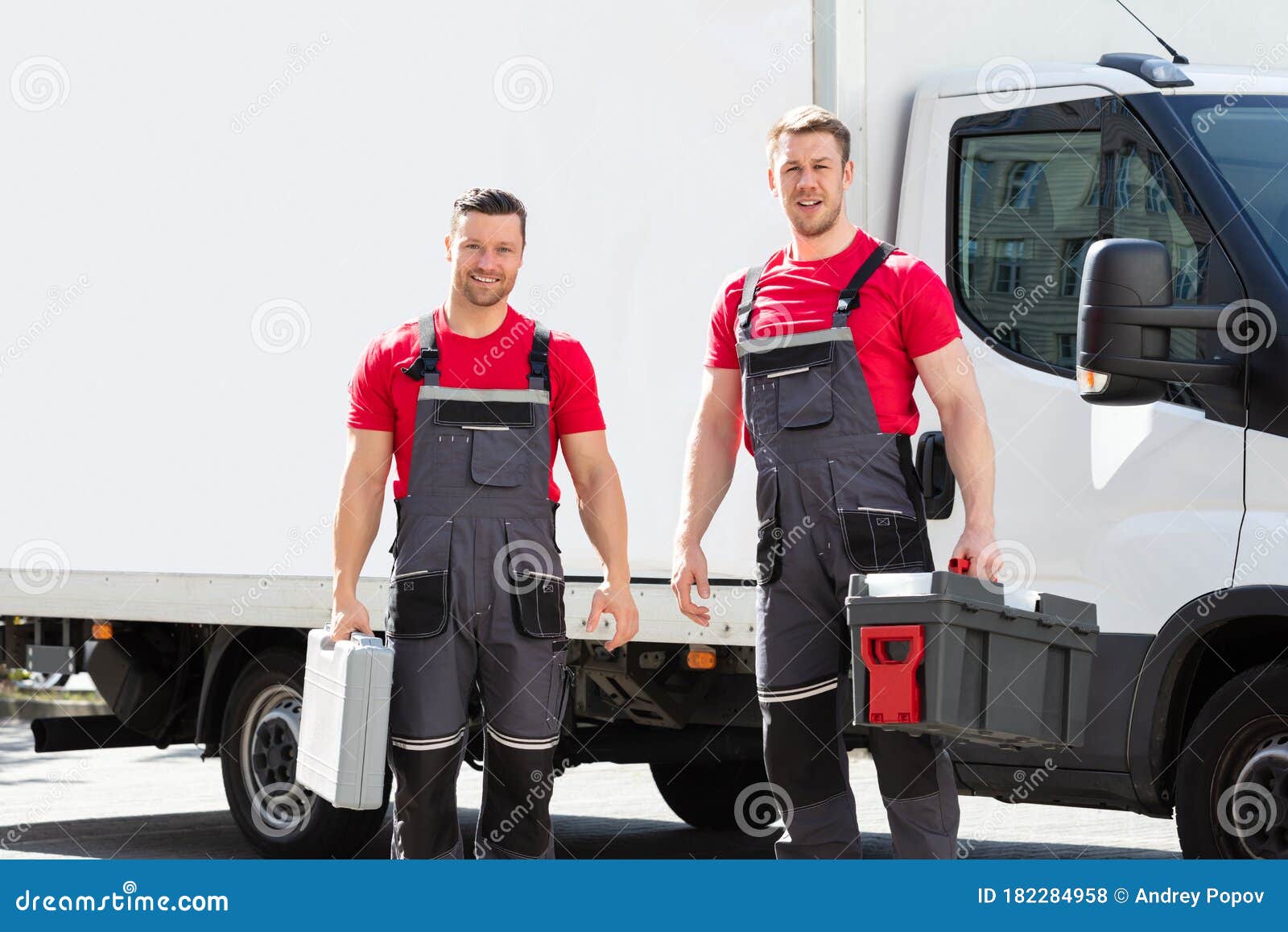 portrait of a smiling young male technicians holding tool box