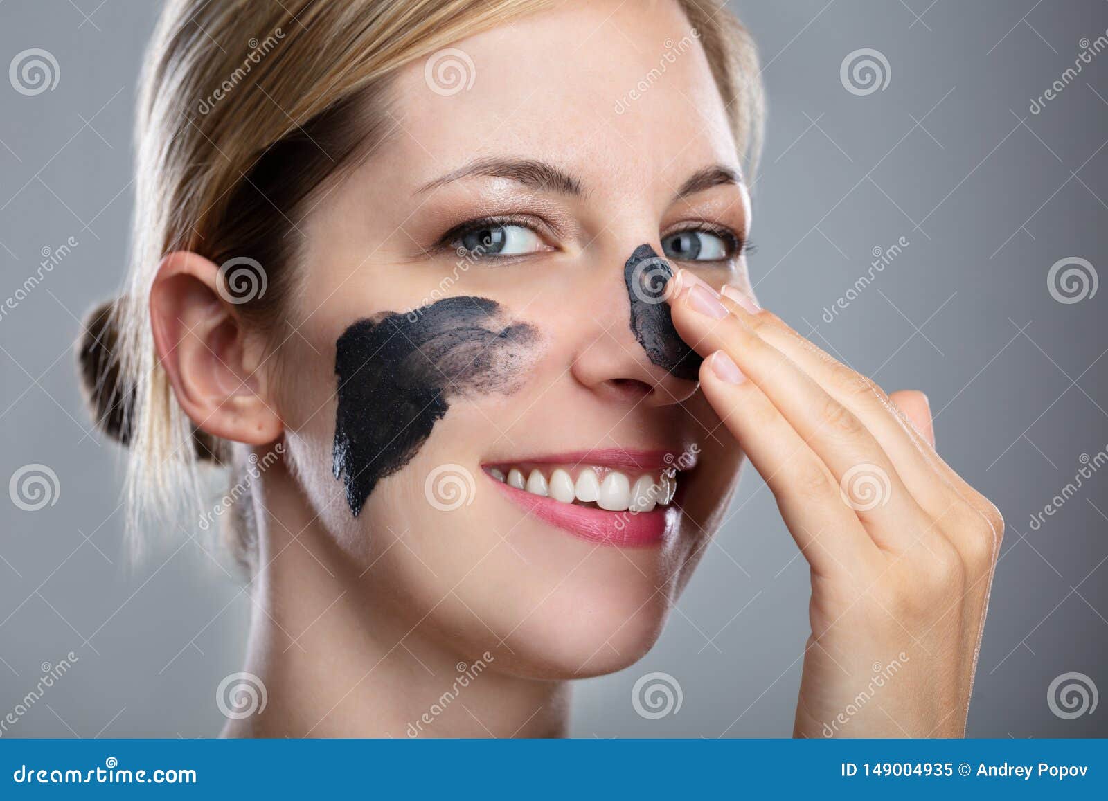 woman applying activated charcoal mask on her face