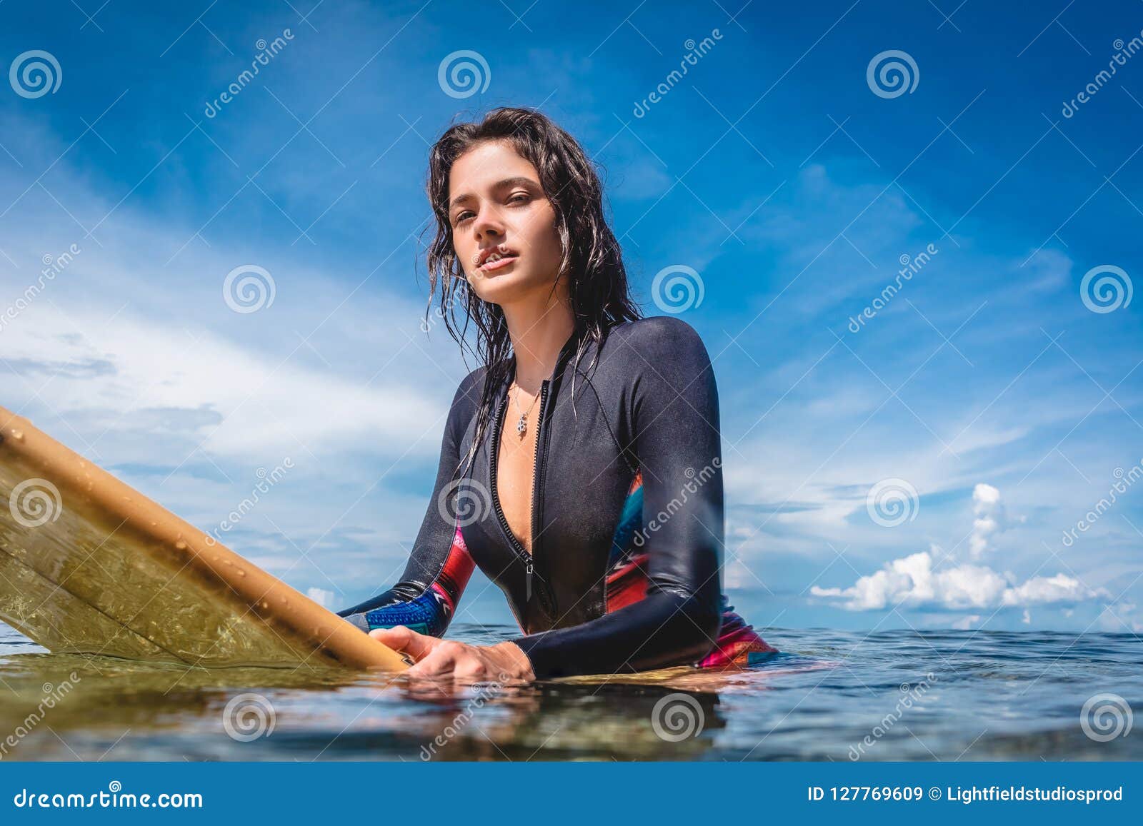 Portrait of Sportswoman in Wetsuit on Surfing Board in Ocean at Nusa