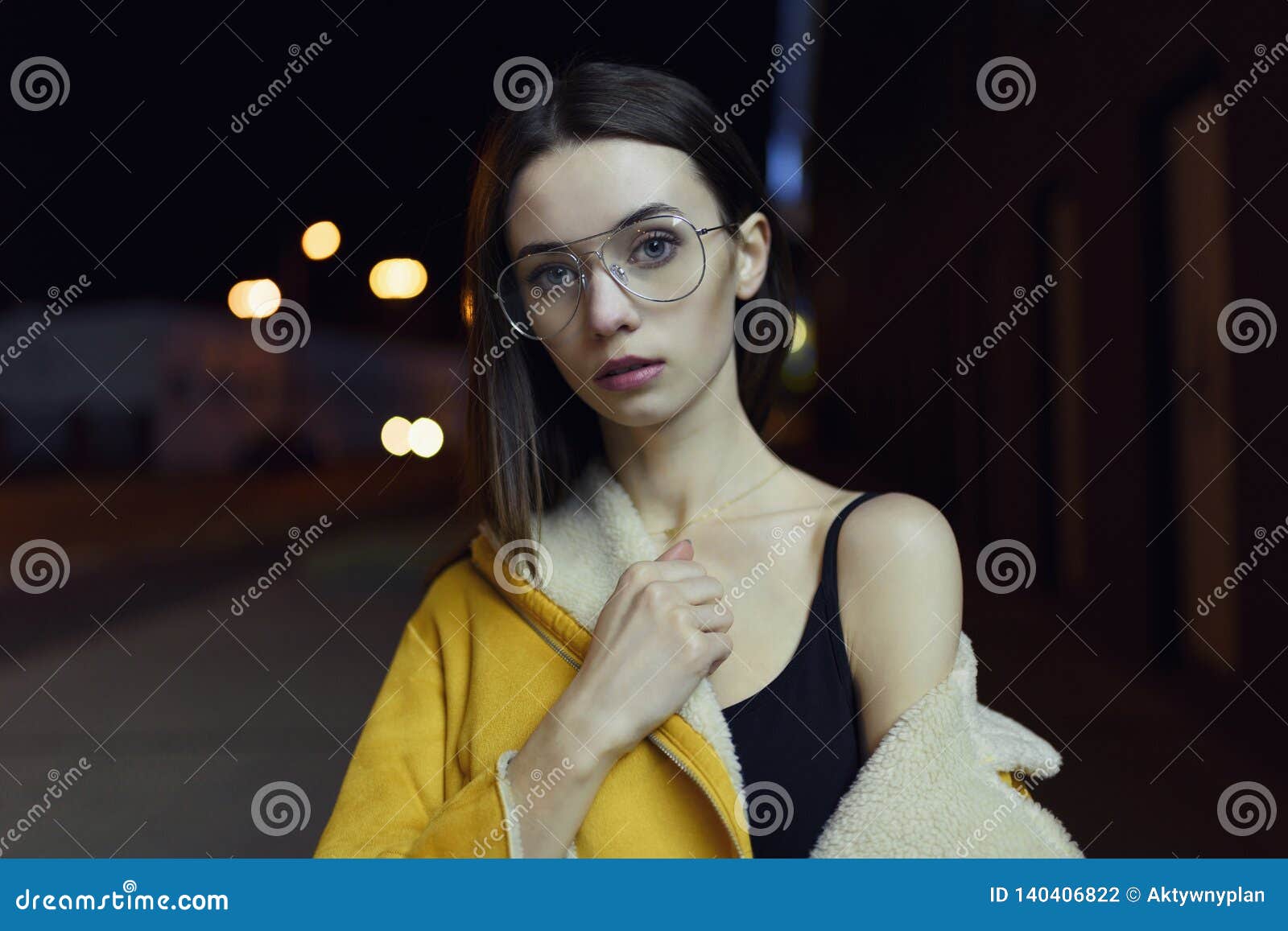 Portrait of Stylish Girl, Posing in Yellow Jacket, Glasses, Lit by City ...