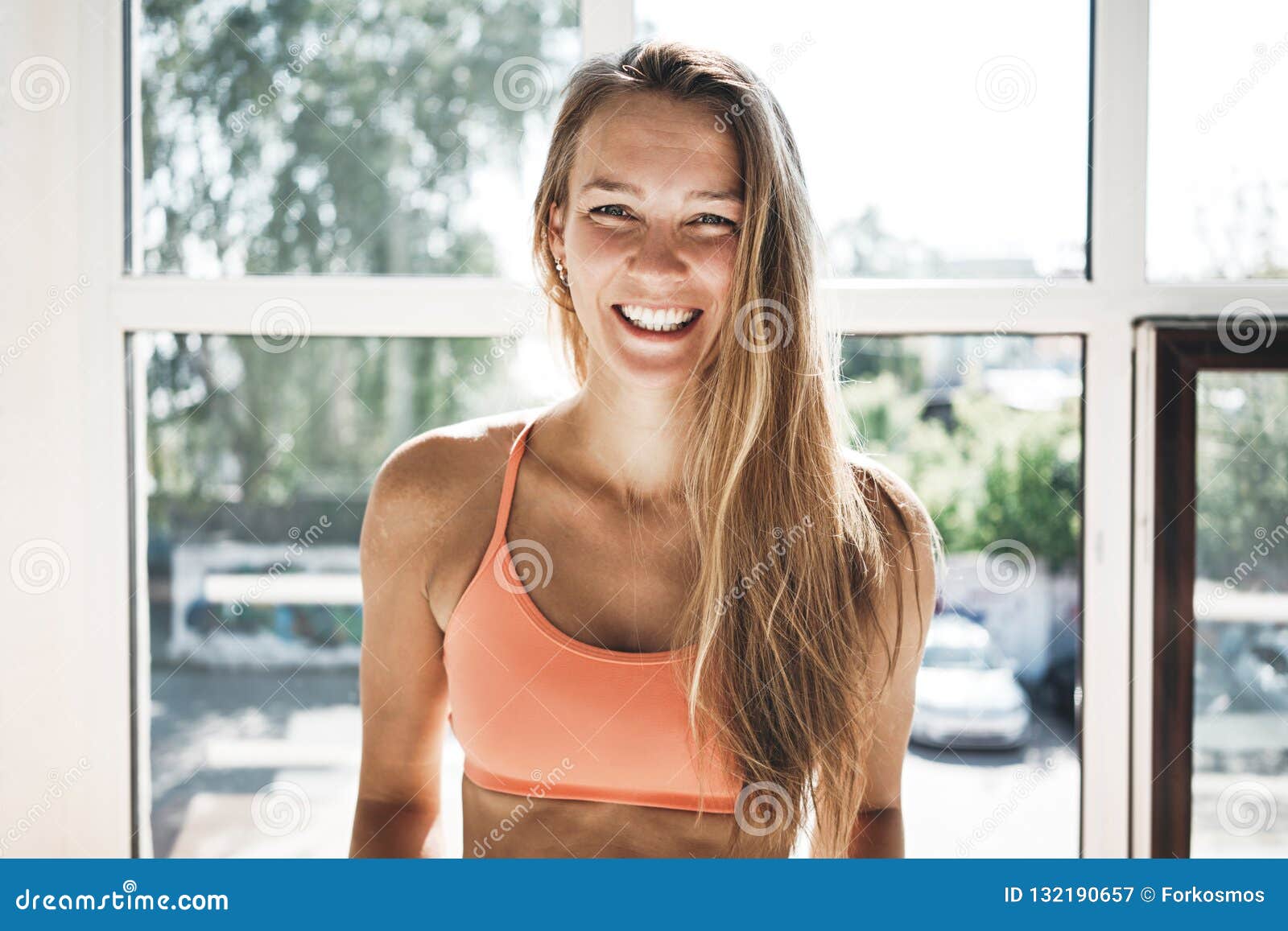 portrait of sunburn fit woman wearing sportwear in sunny white gym